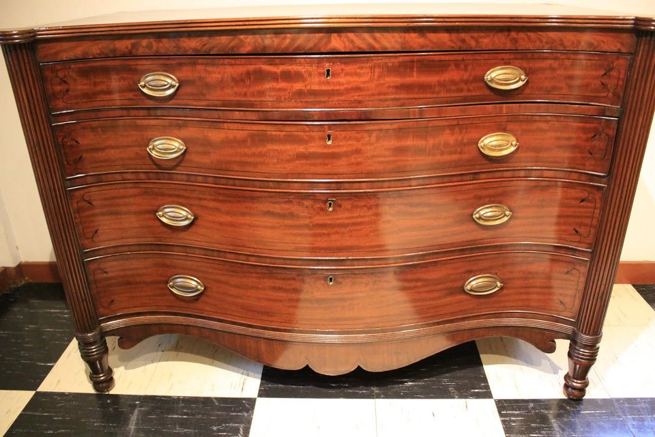 English Regency chest of drawers in figured mahogany with four graduated drawers. And ebony stringing to the top, drawer fronts and apron. Fluted columns end in turned and beaded feet. Beaded top edge and apron.