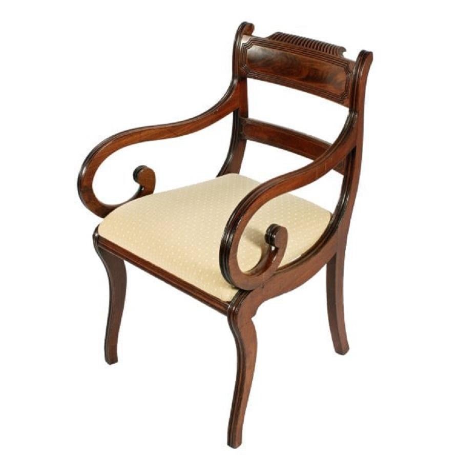 An early 19th century Regency mahogany sabre leg elbow chair.

The chair has an inset back top rail with a carved and reeded detail, the centre having a figured mahogany veneered panel.

The middle rail has the same figured mahogany panel in the
