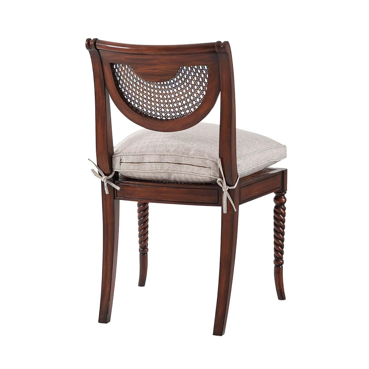 A hand-carved side chair, the verdigris brass oval inset and caned back above a silk tie on cushion seat, on spiral turned legs. The original Regency.

Dimensions: 22