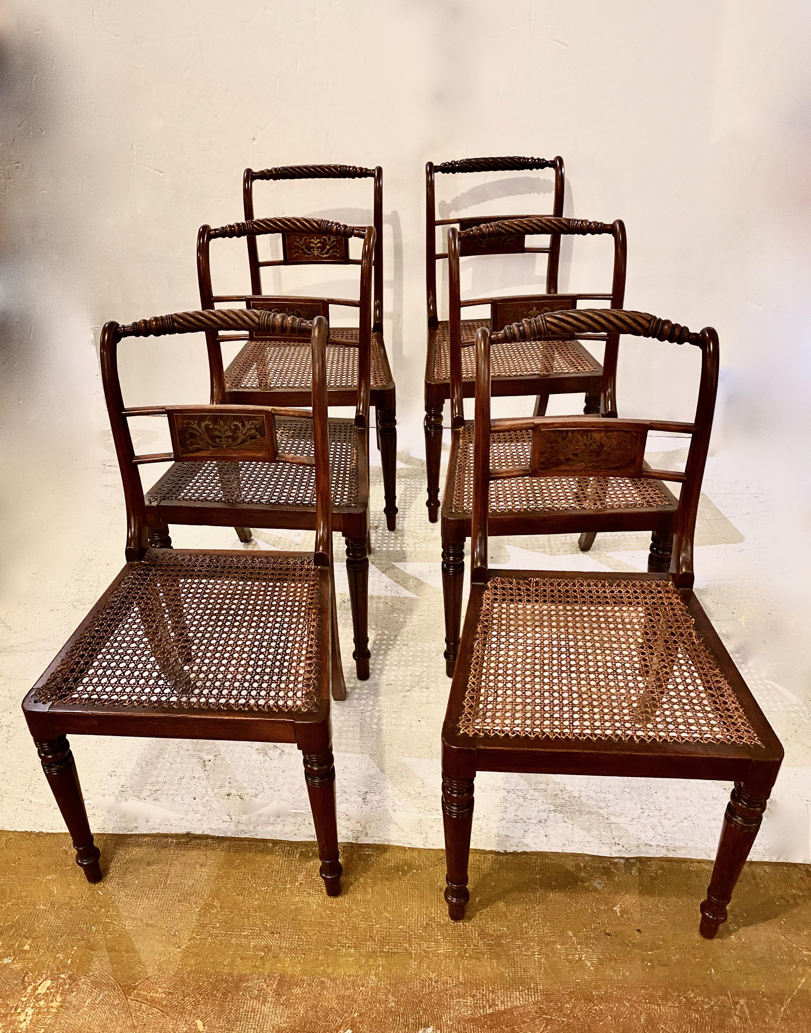 This is a very good set of 6 English Regency solid mahogany side or dining chairs of a modified klismos form. The chairs feature a well-carved rope top rail that, together with the foliate brass inlaid center splat, are testimony to the chairs'