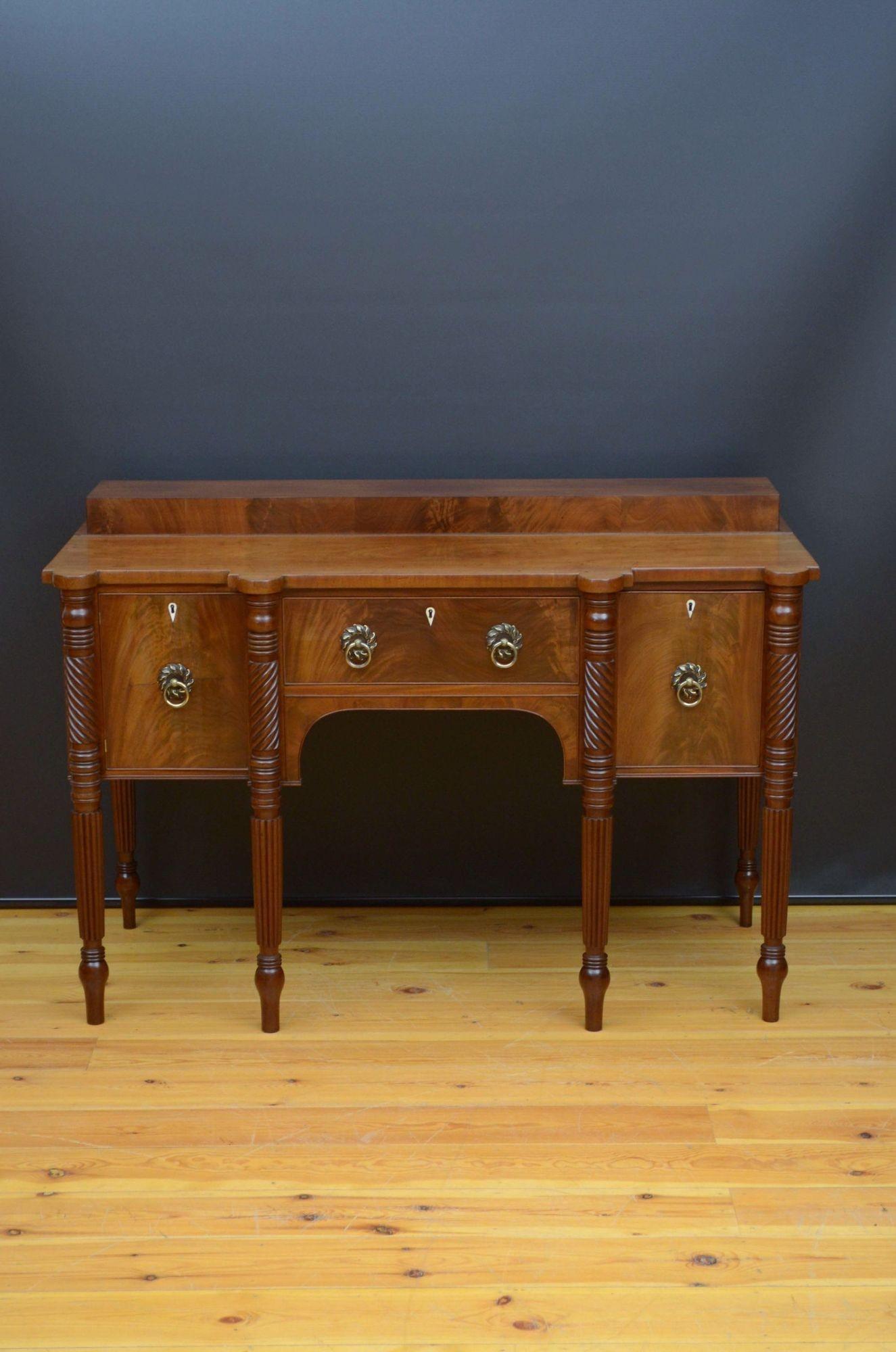 A01 Fine quality Regency sideboard in mahogany, having figured mahogany top above flamed mahogany centre drawer flanked by flamed mahogany cupboard and flamed mahogany deep drawer with bottles compartments, all with cockbeading, bone escutcheons,