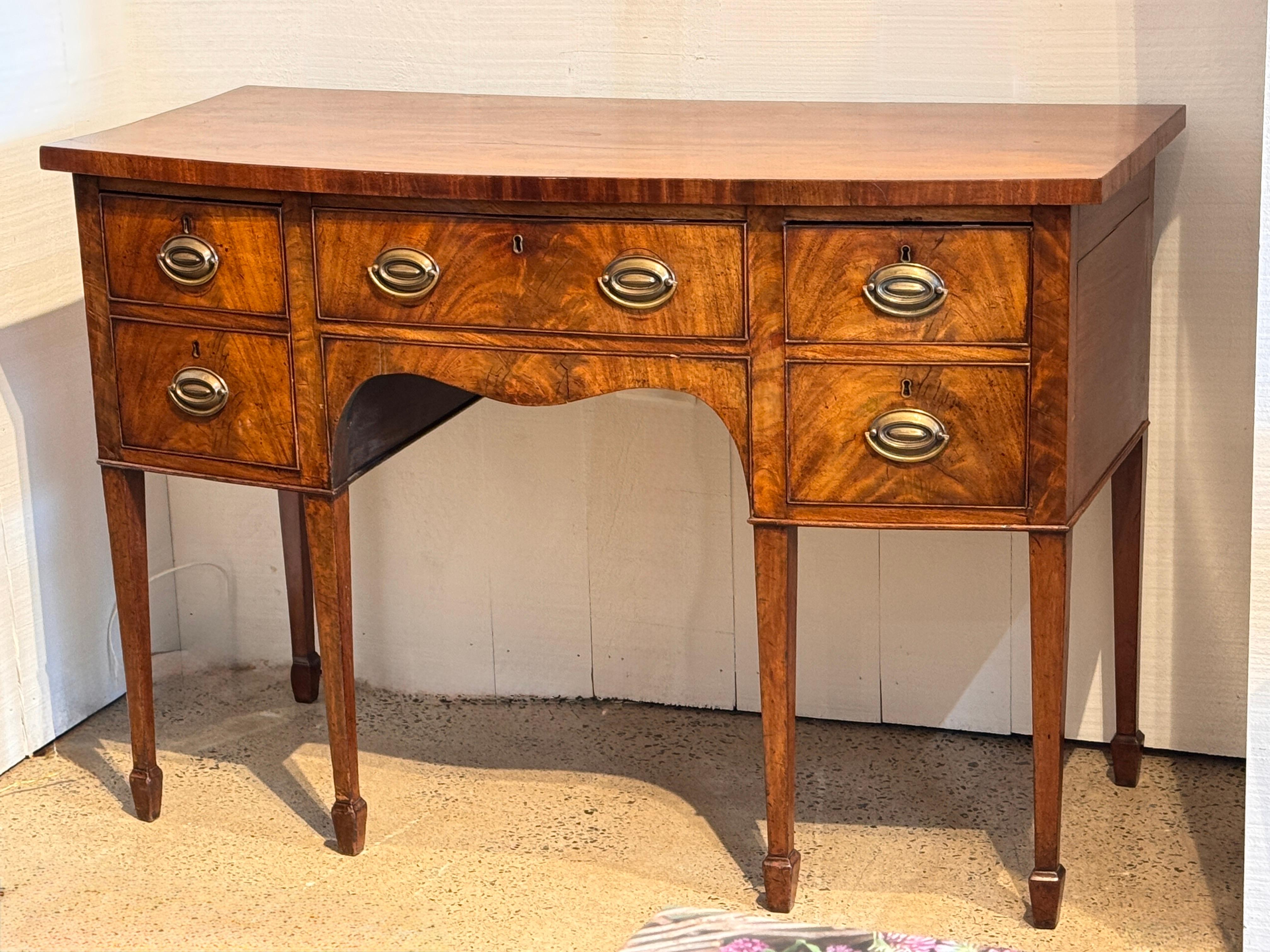 Buffet d'époque Régence en acajou avec une forme en arc de cercle et un placage richement figuré. Le tiroir central est flanqué de rangées de tiroirs, dont l'un est équipé d'une cellarette divisée et doublée de plomb, utilisée à l'origine pour