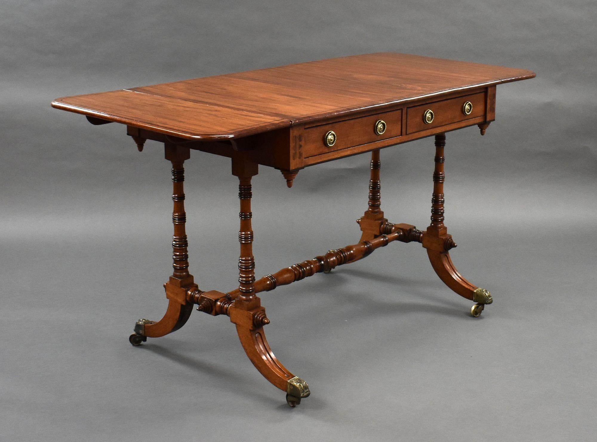 For sale is a good quality Regency mahogany sofa table, having two drawers to the front, and two faux drawers on the opposing side, supported by turned columns united by a turned stretcher, the table stands on elegant splayed legs raised on brass