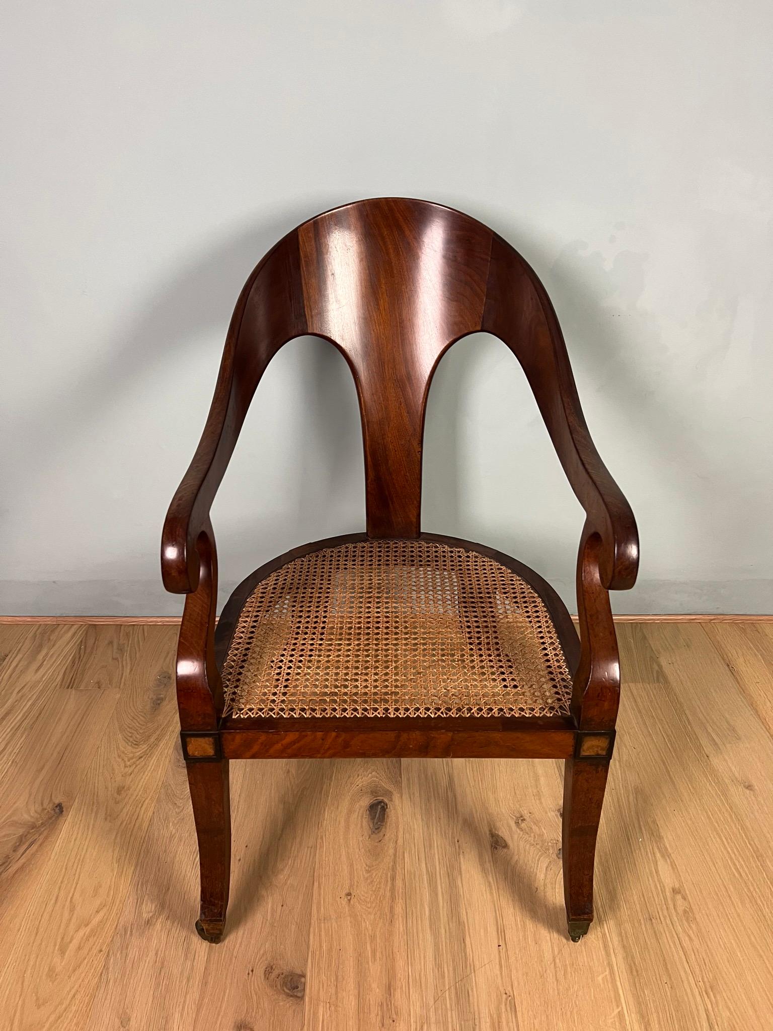 This Regency mahogany Roman spoon back Bergere armchair has a wonderful flowing shape to it’s cresting rail, classical sweeping arms and sabre front and back legs finishing on square tapered brass casters. The seat is traditionally caned and the