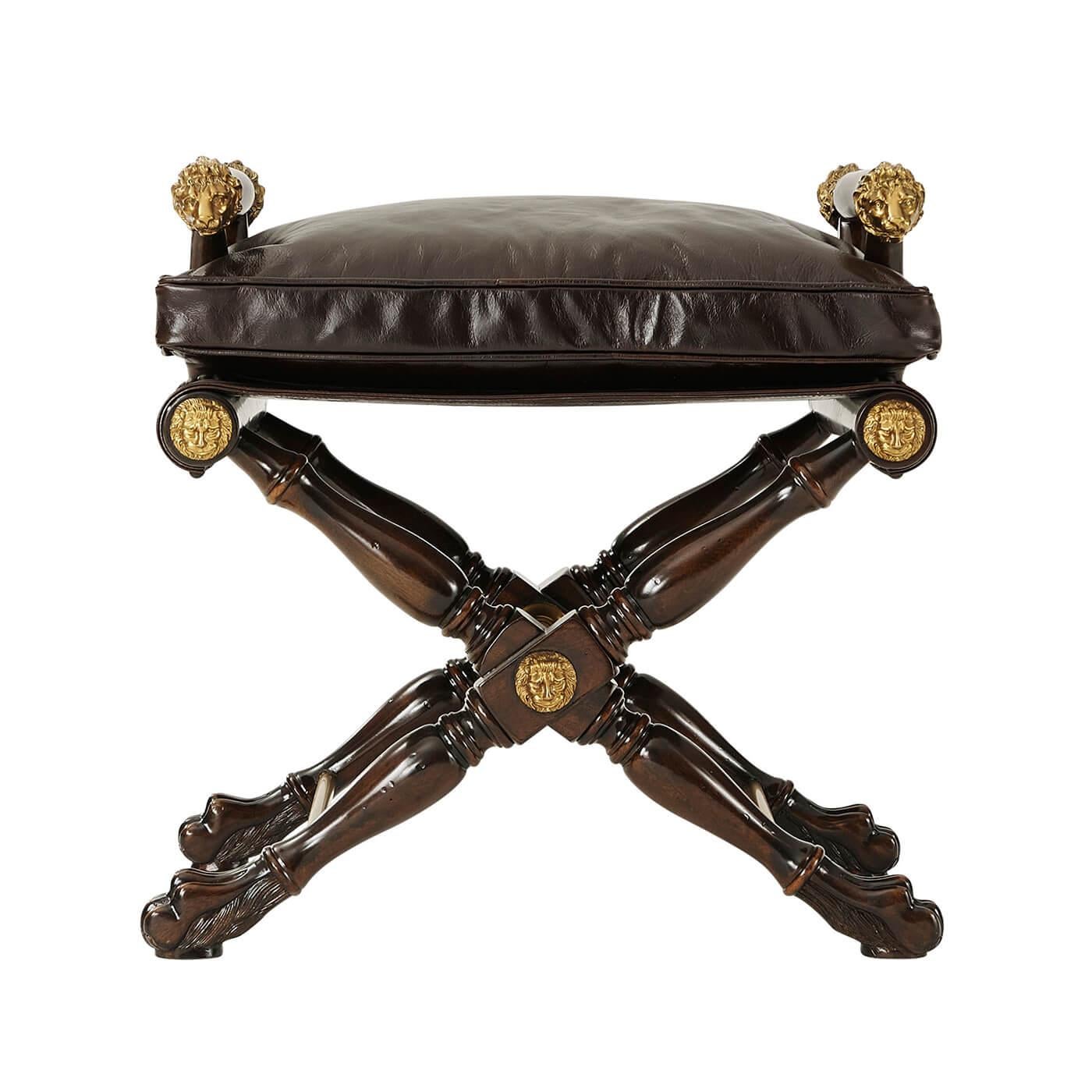A Regency style mahogany and brass mounted stool in the manner of Thomas Hope, with slung seat, lion head arm terminals, on a turned 