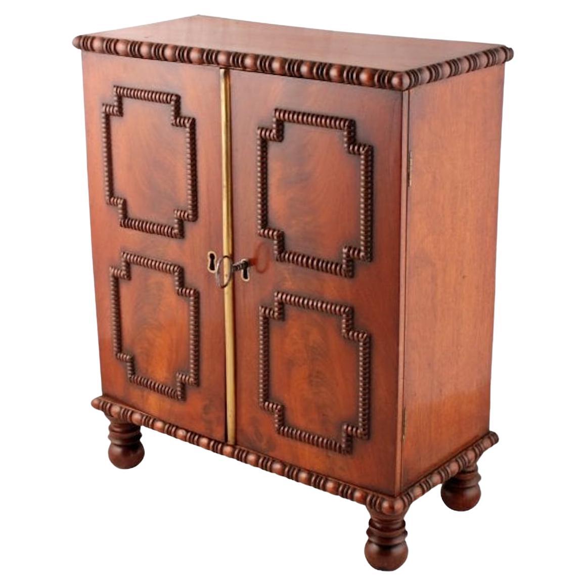 Regency Mahogany table cabinet

An early 19th century Regency mahogany two door table cabinet.

The cabinet is decorated with half round bobbin turned mouldings to the top and bottom edges and doors.

Where the doors meet is a gilt brass half