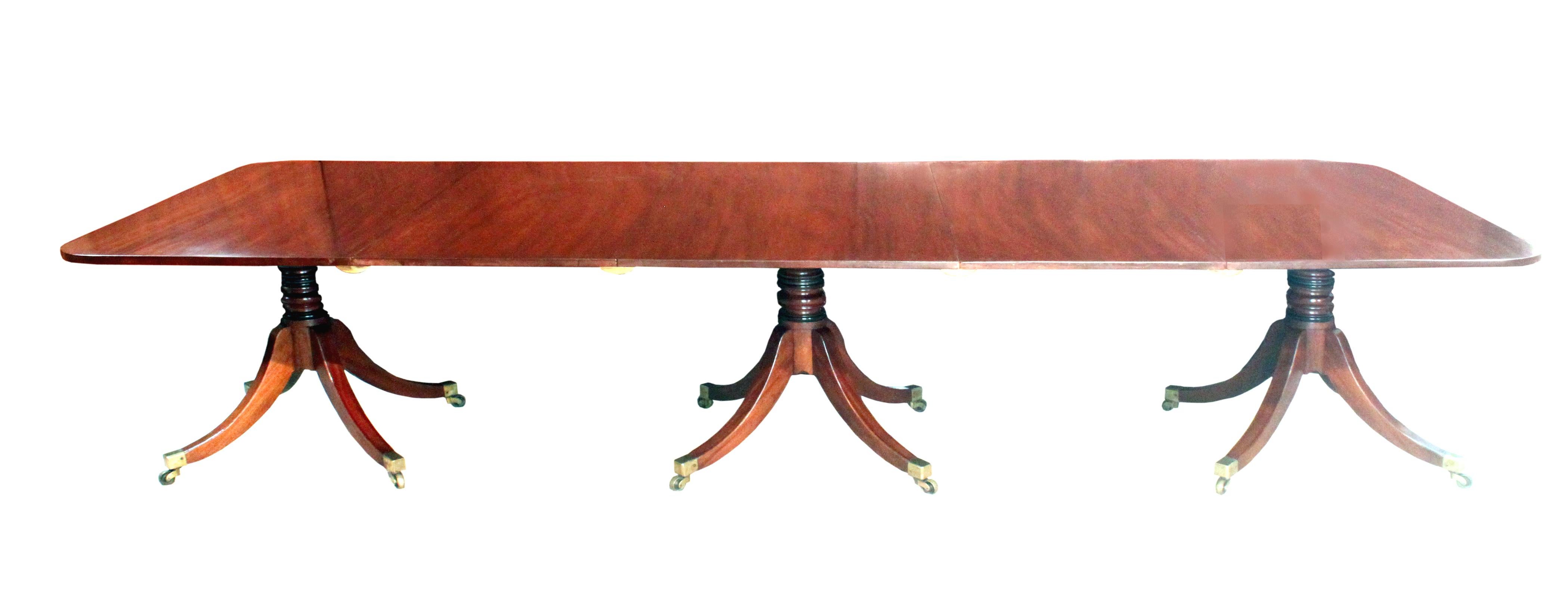 A good Regency triple pillar dining table in figured mahogany, only 48” wide, handsome four splay pedestals with their original tops, the stems with 2 ebonised turnings matching the black ebony stringing in the sabre legs. The castors stamped with a