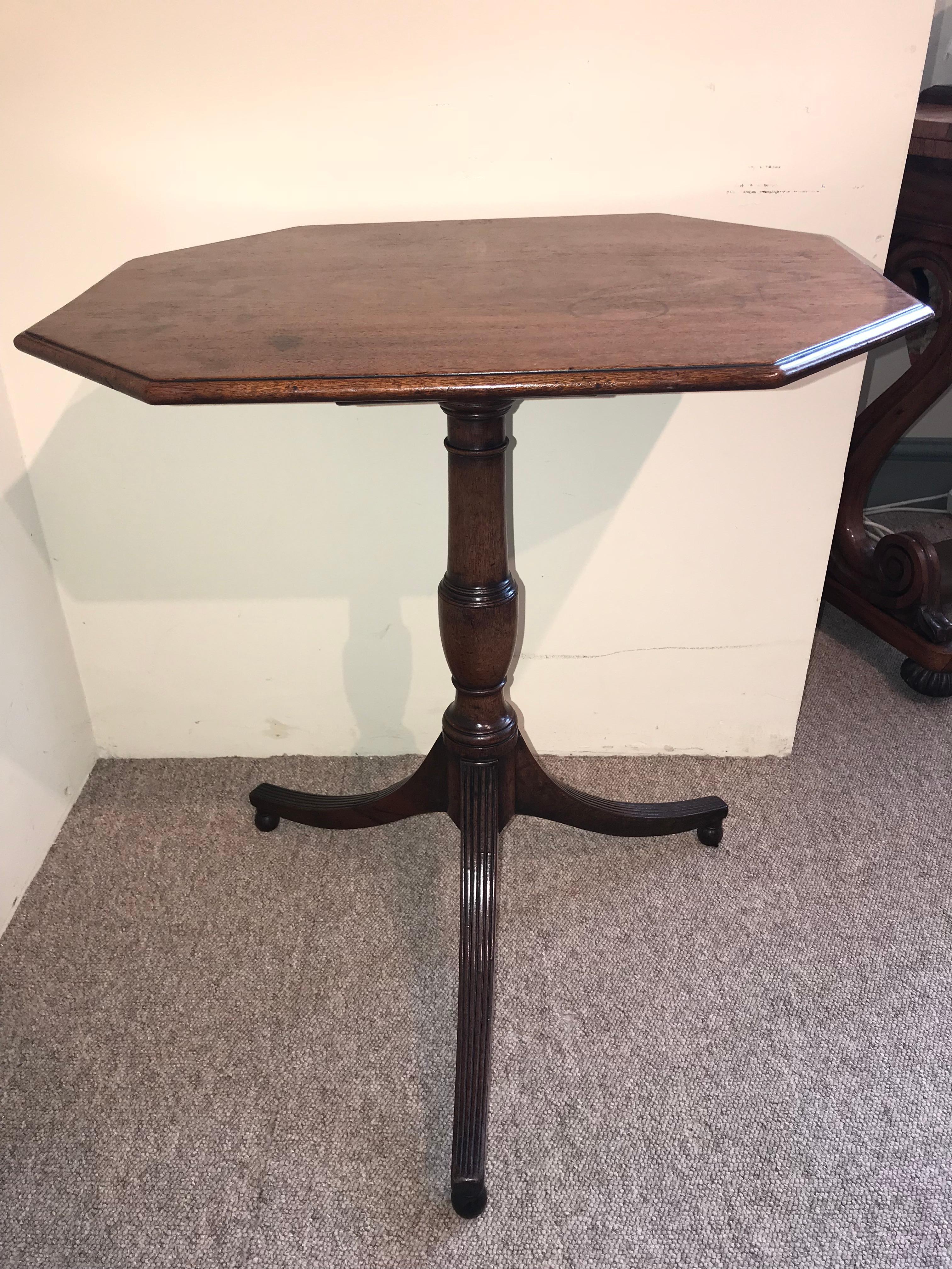 Elegant Regency period octagonal tilt top tripod wine table with a solid mahogany turned stem ending on three out swept and fluted legs.