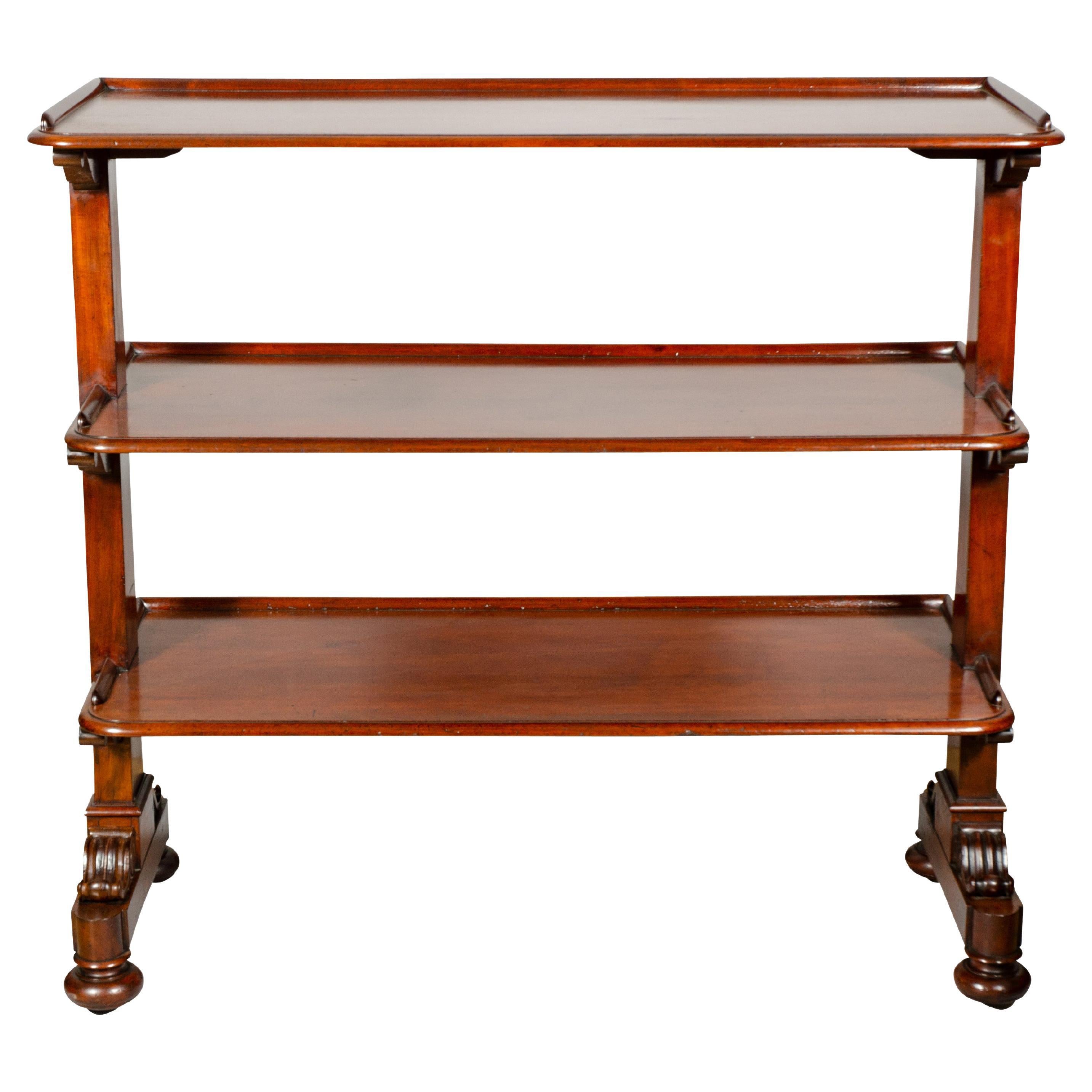 Most likely by Gillows of Lancaster. Excellent timber. Three shelves each with molded edges and carved volute brackets and panelled ends, raised on flattened ball feet with casters. These were used in dining rooms as a trolley for silver and dinner