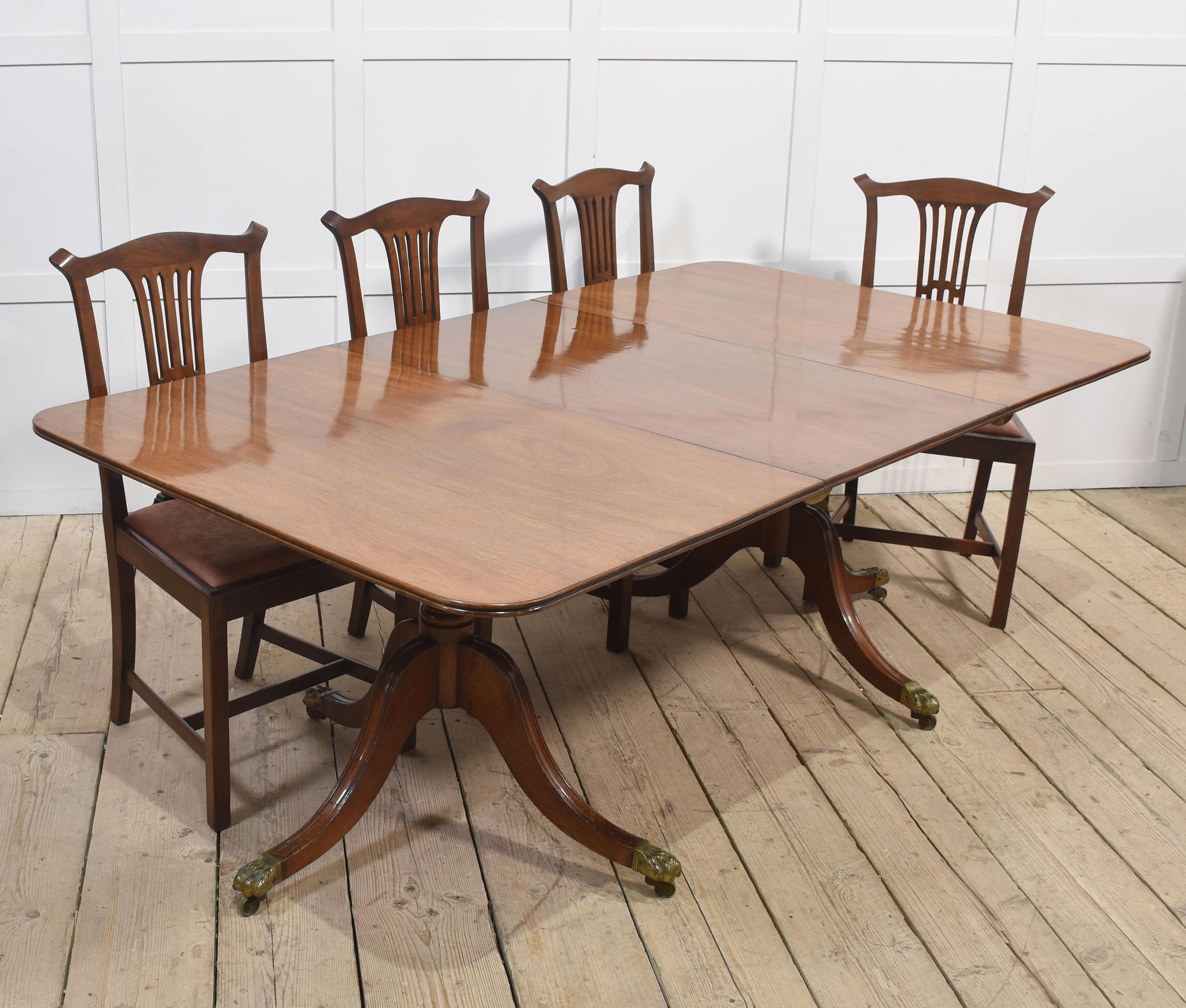 Regency dining table, the large rectangular top with rounded corners and moulded edge opening to incorporate additional leaf. Raised up on two pedestals with turned detail supported on three sabre legs terminating in brass capped paw feet and