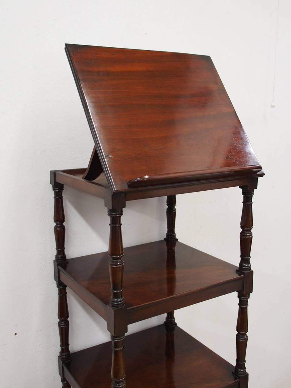 Regency whatnot in figured Spanish mahogany, all supported on very fine ring turned supports on brass castors, circa 1820. The top tier acts as an adjustable book rack and beneath the lower tier is a single drawer with finely turned wooden knobs.