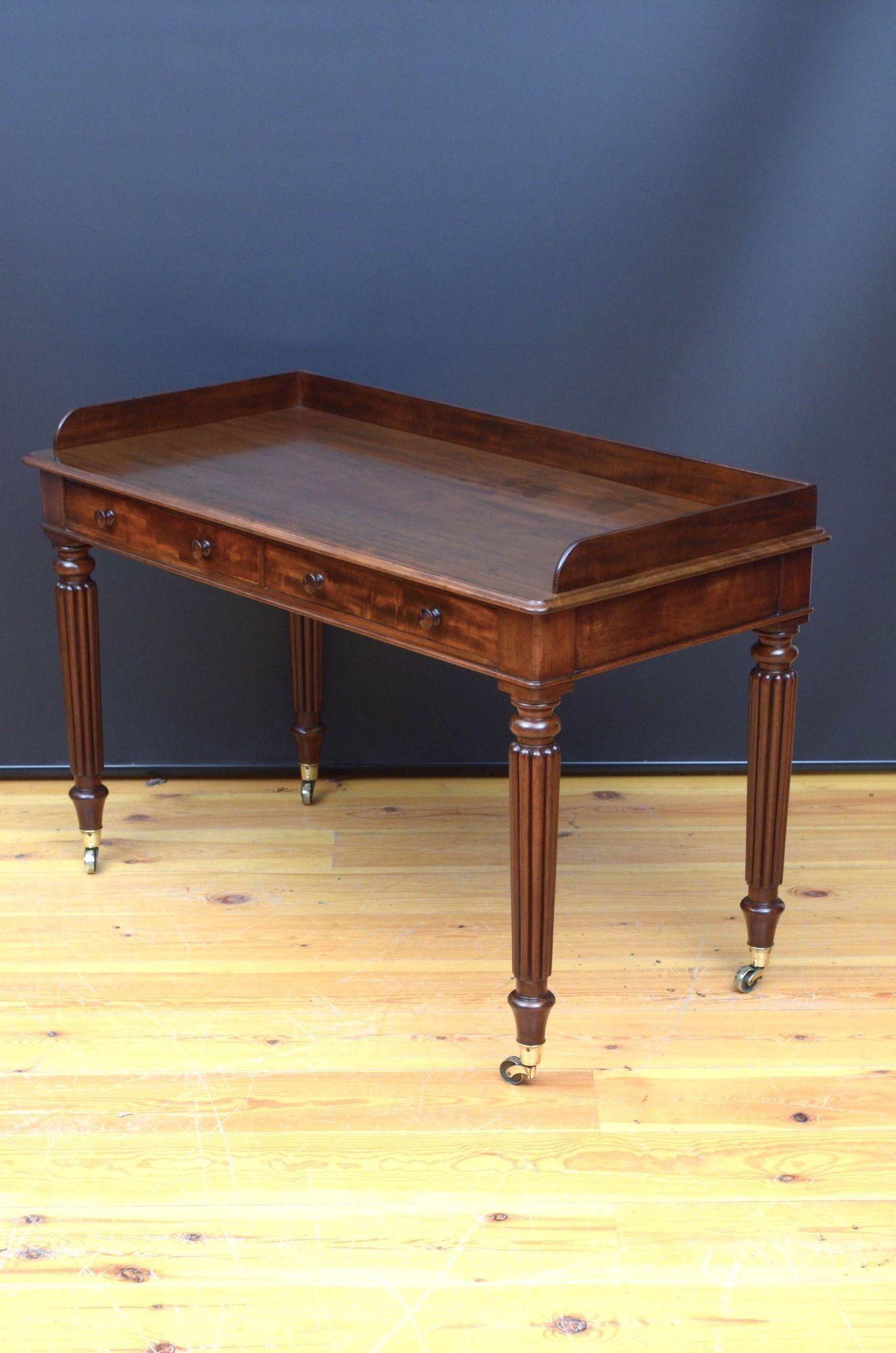St037 Fine quality Regency dressing table / writing desk in mahogany, having shaped upstand, figured mahogany top with moulded edge and two oak lined drawers fitted with turned knobs, all standing on turned and fluted legs terminating in original