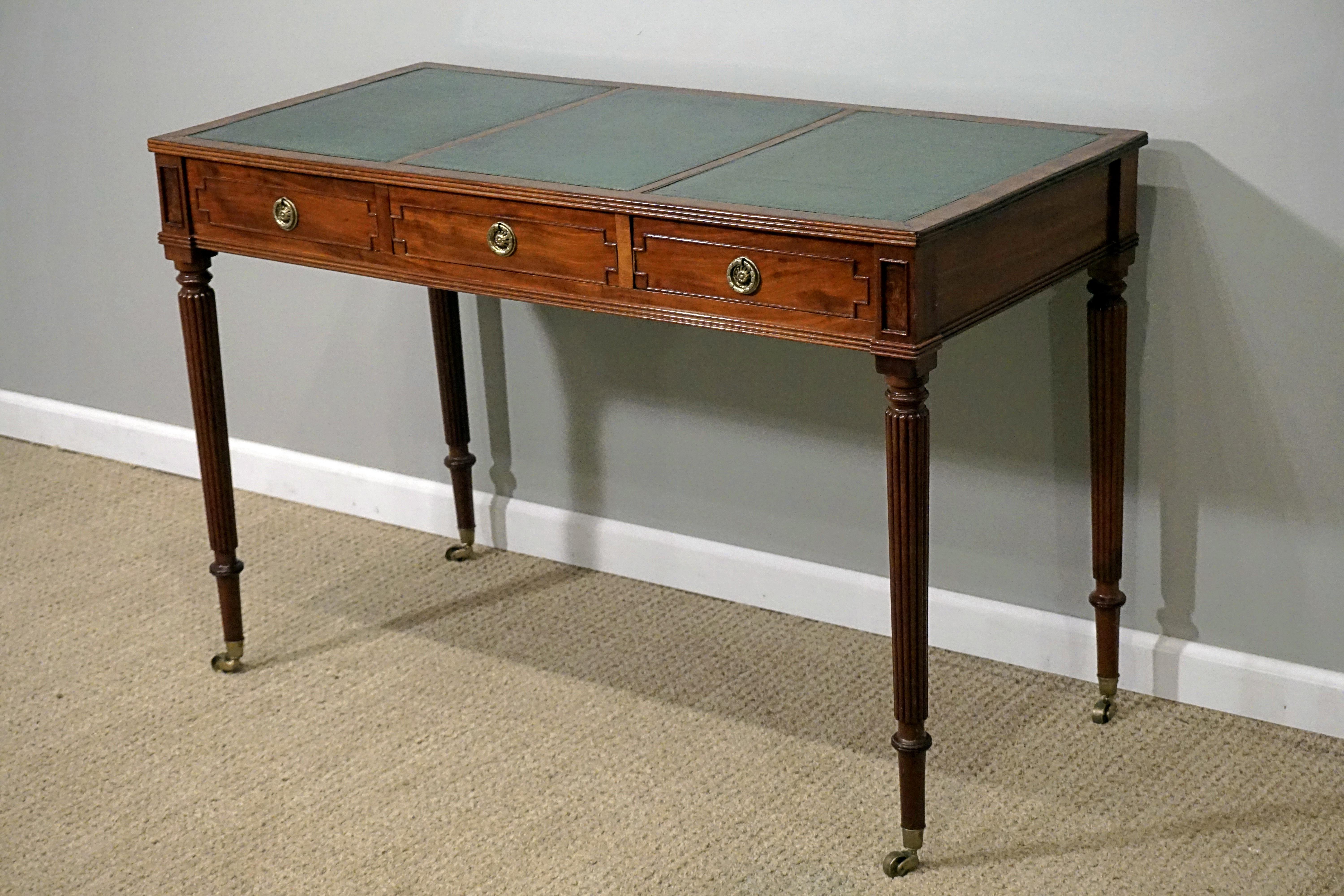 Regency mahogany writing table with leather desktop and brass accents and castors.