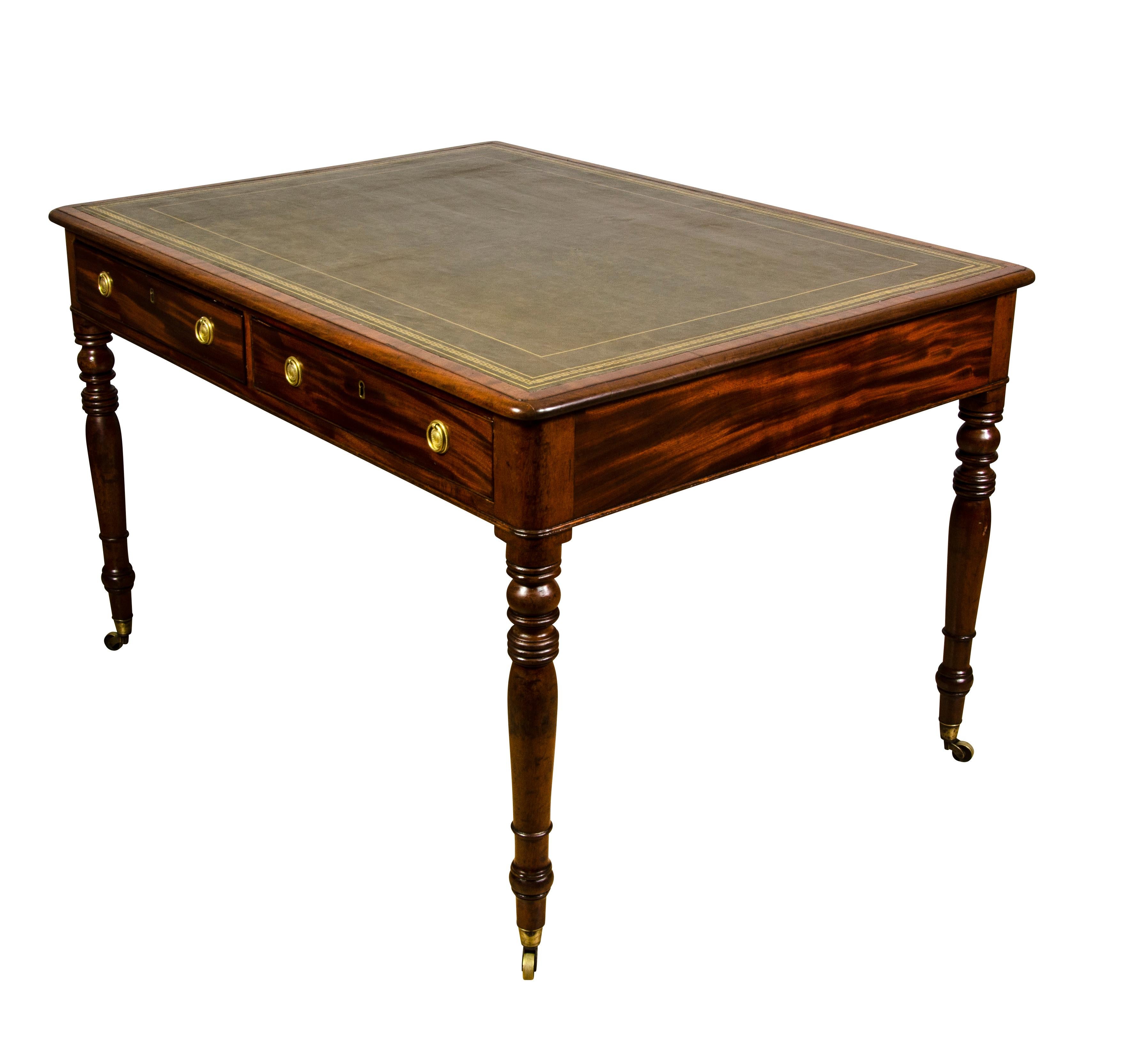 With rectangular inset green tooled leather top with cross banded and rounded edge over two drawers and opposing drawers raised on circular tapered legs and casters.