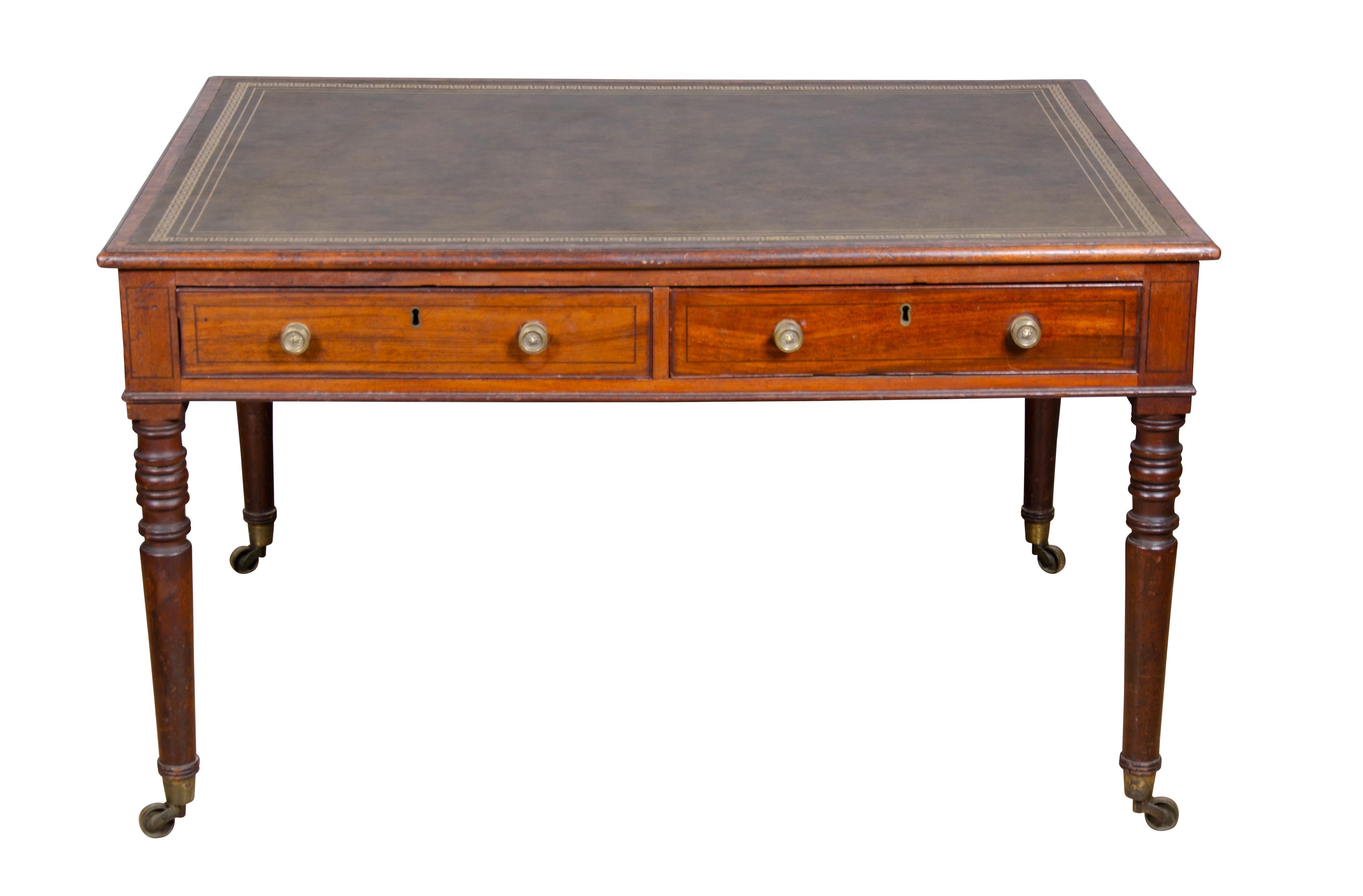 With rectangular top with tooled green leather over two drawers and two opposing drawers with brass knobs, raised on circular tapered legs and casters.