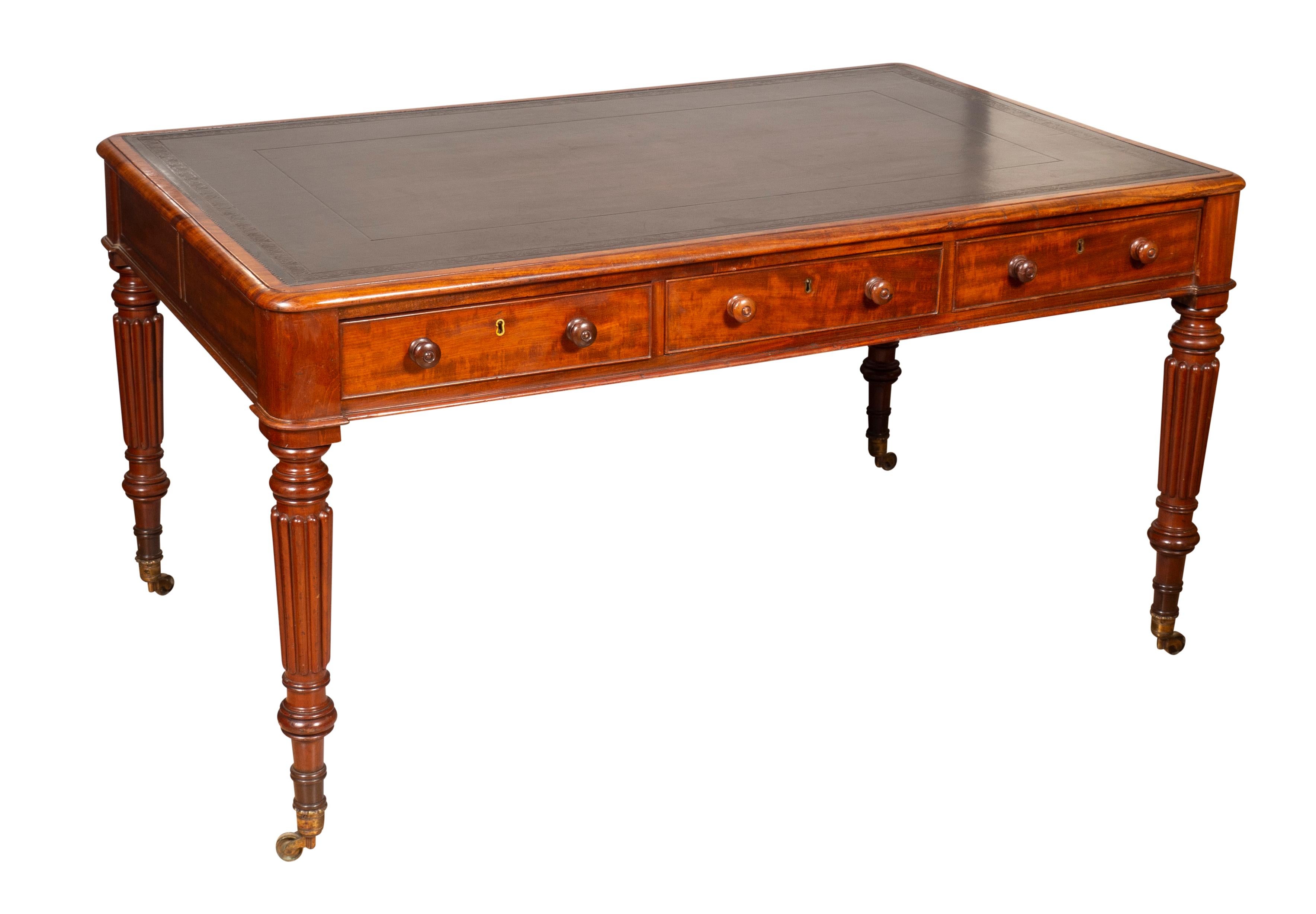 With a rectangular top with inset black leather over a frieze containing three drawers.The reverse with paneled back and ends and raised on turned reeded legs and casters. Probably by Gillows of Lancaster. Generous scale with good leg room.