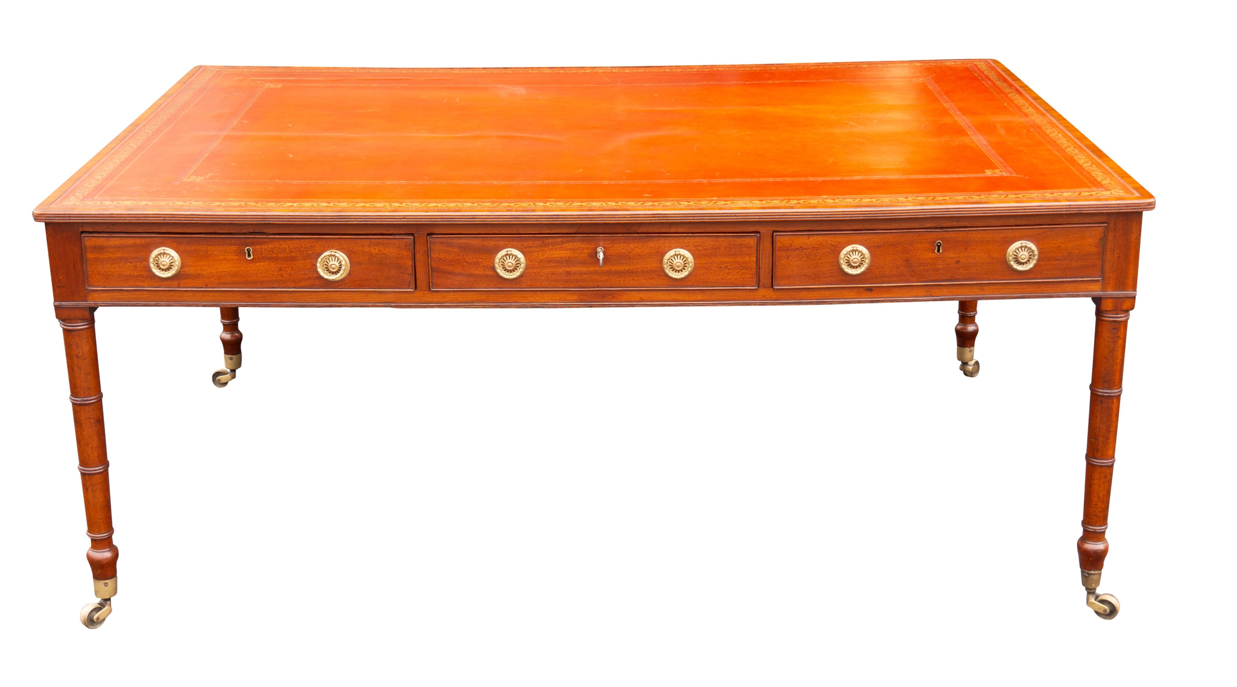 Rectangular red tooled leather top with cross banded edge over three drawers and three on the reverse, all working so can function as a partners desk with brass ring handles. raised on circular tapered legs ending on casters. Sold Bonhams London
