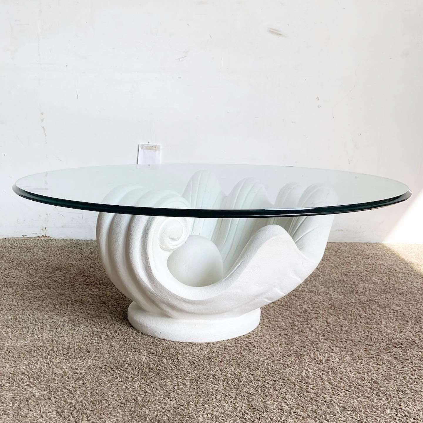Introducing the Regency Modern White Plaster Clam Shell Glass Top Coffee Table. This piece seamlessly blends timeless elegance with coastal charm. With its white plaster base shaped like a clam shell and a transparent glass top, it's both functional