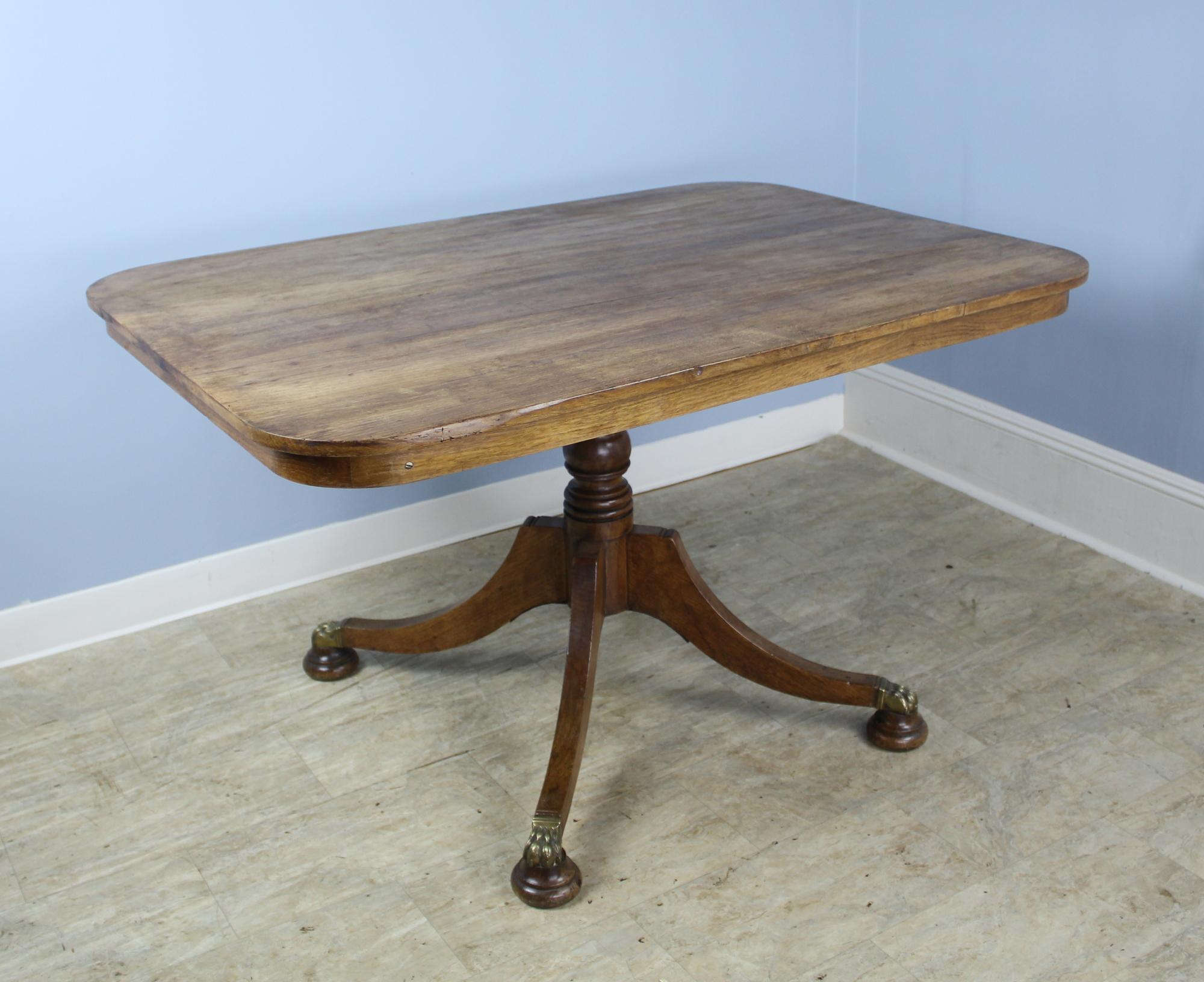 A versatile gaming or breakfast table with a tilt-top mechanism for easy storage. The generously proportioned top has a smooth oak grain and lovely patina. The flared pedestal base and stylized brass feet bring true elegance. The latch to open and