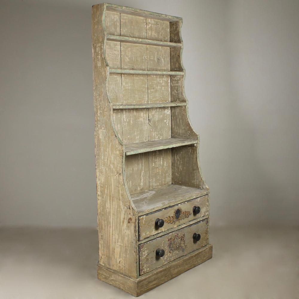 A large scale, early 19th century pine waterfall bookcase, dry scraped back to its original paint. With line, cartouche with leaf sprays and armorial decoration, also retaining its original handles.
English, circa 1820.