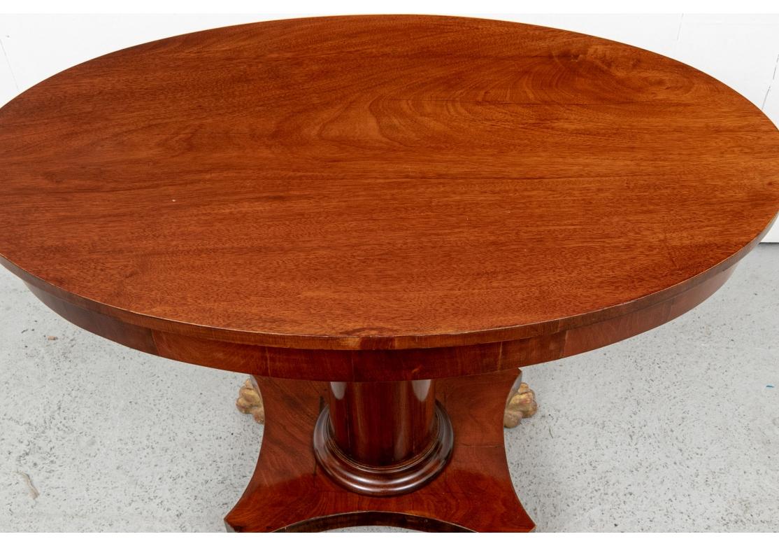 A fine Regency mahogany oval table with a large column support mounted on a four part curved base ending in large carved and gilt lion's paw feet. In a fine polish. 
L. 38 1/4