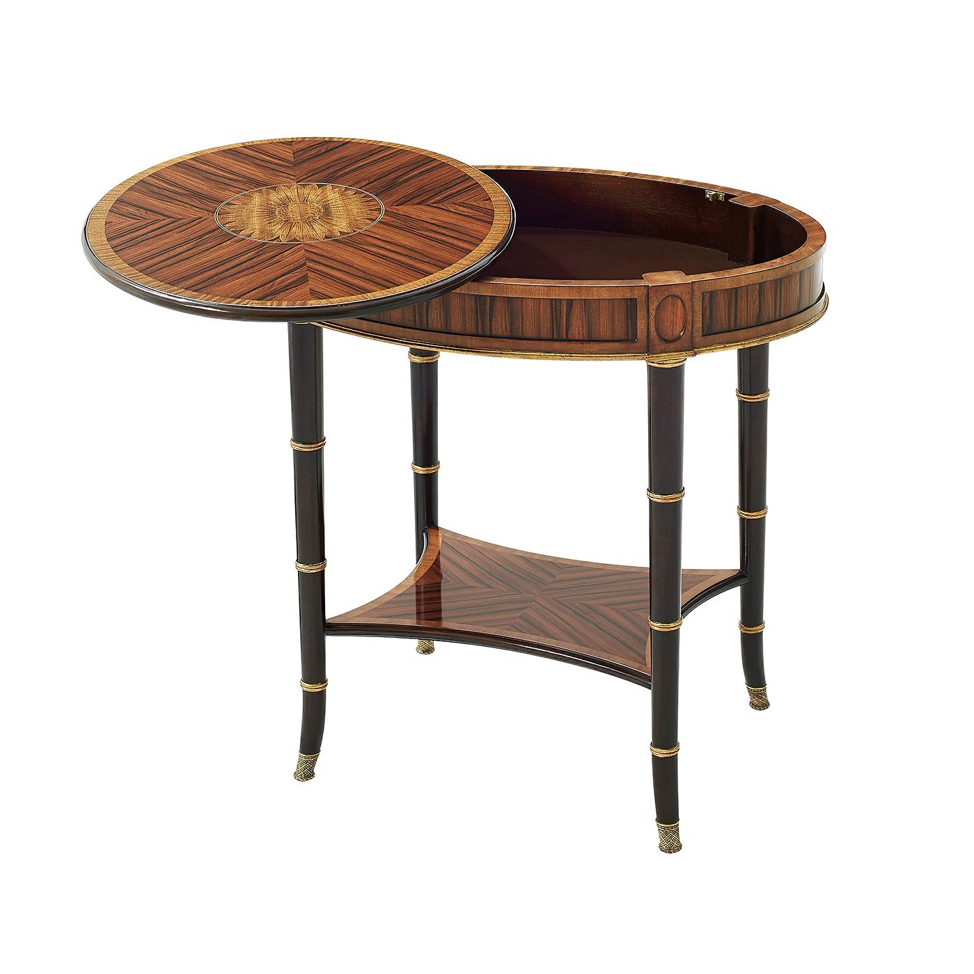 A Regency style oval side table, with a Morado and satinwood veneers, the oval molded edge top with a floral oval penwork detail inlay, above a crossbanded frieze and on ebonized and gilt ring turned mahogany splayed legs terminating in finely cast