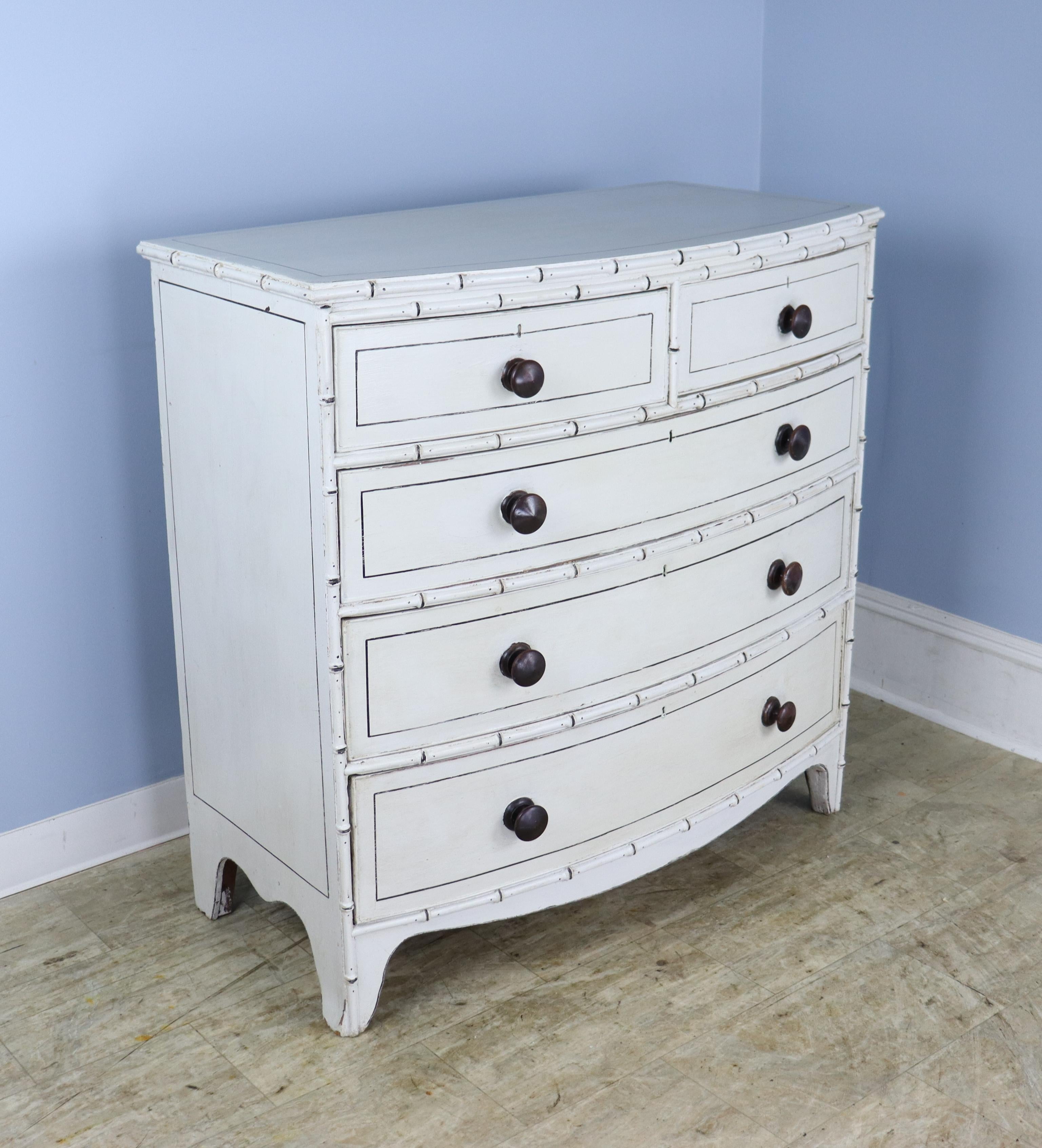 A charming Regency bowfront chest of drawers with bamboo detail, newly painted in an antique creamy white, finished with beeswax to create a faux distressed effect. Perfectly suited to a beach cottage, child's room or guest room. Roomy drawers open