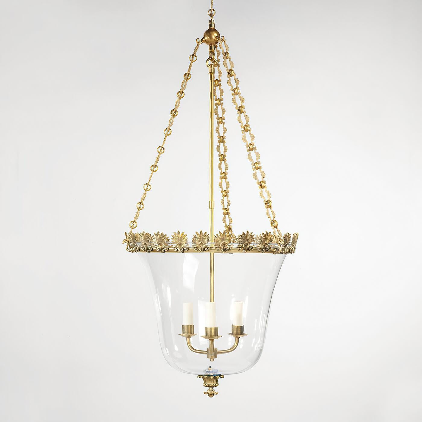 Regency Palmette Cloche lantern, this three-light lantern design features intricate metalwork and a decorative hand-blown globe. The acanthus leaf Palmette motif on the band and the ornate chain, complement the simple glass bowl. Fabricated from