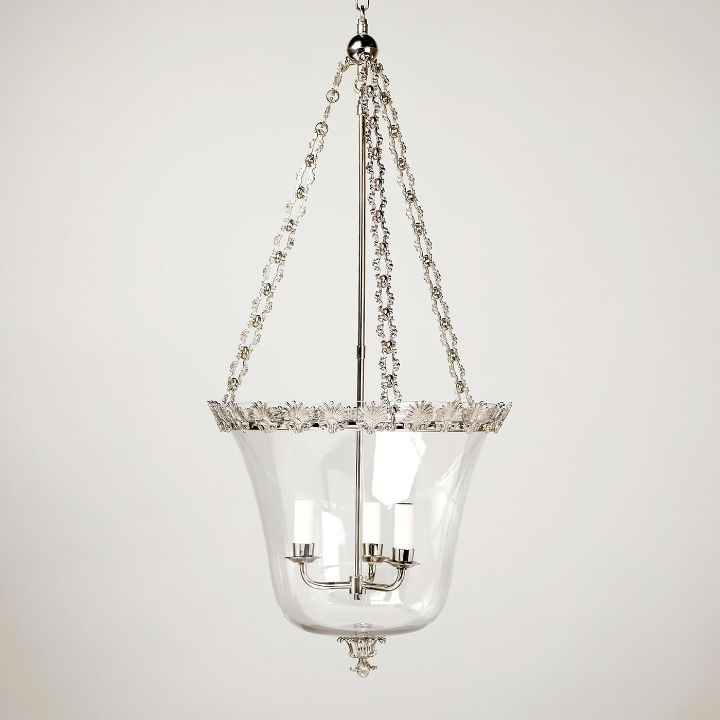 Regency Palmette cloche lantern, this three-light lantern design features intricate metalwork and a decorative hand-blown globe. The acanthus leaf Palmette motif on the band and the ornate chain, complement the simple glass bowl. Fabricated from