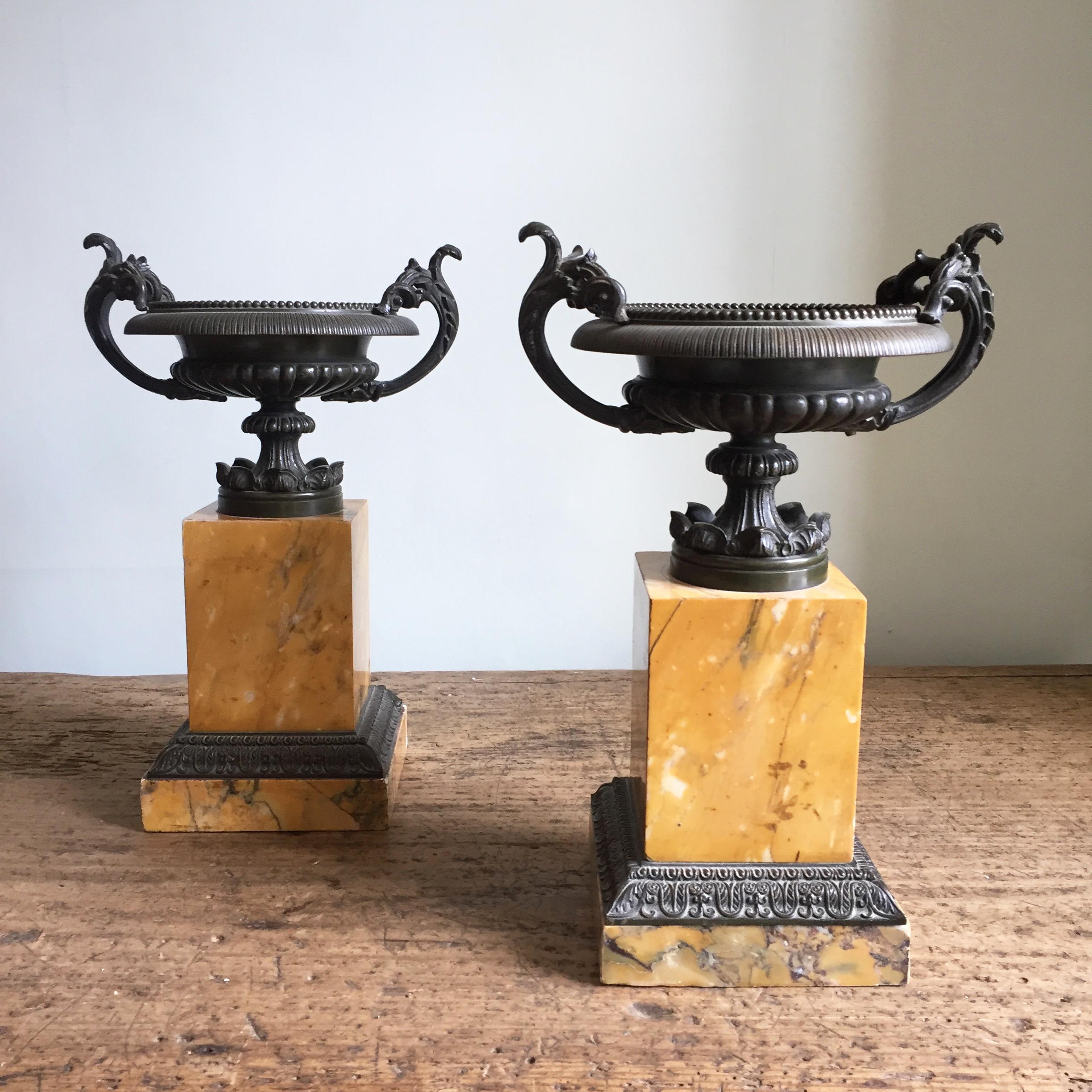 A fine pair of patinated bronze tazza urns on sienna marble plinths with further bronze mounts.

Generally very fine condition despite some nibbles to a few areas of the marble base.

The perfect Grand Tour object for the mantelpiece.
  