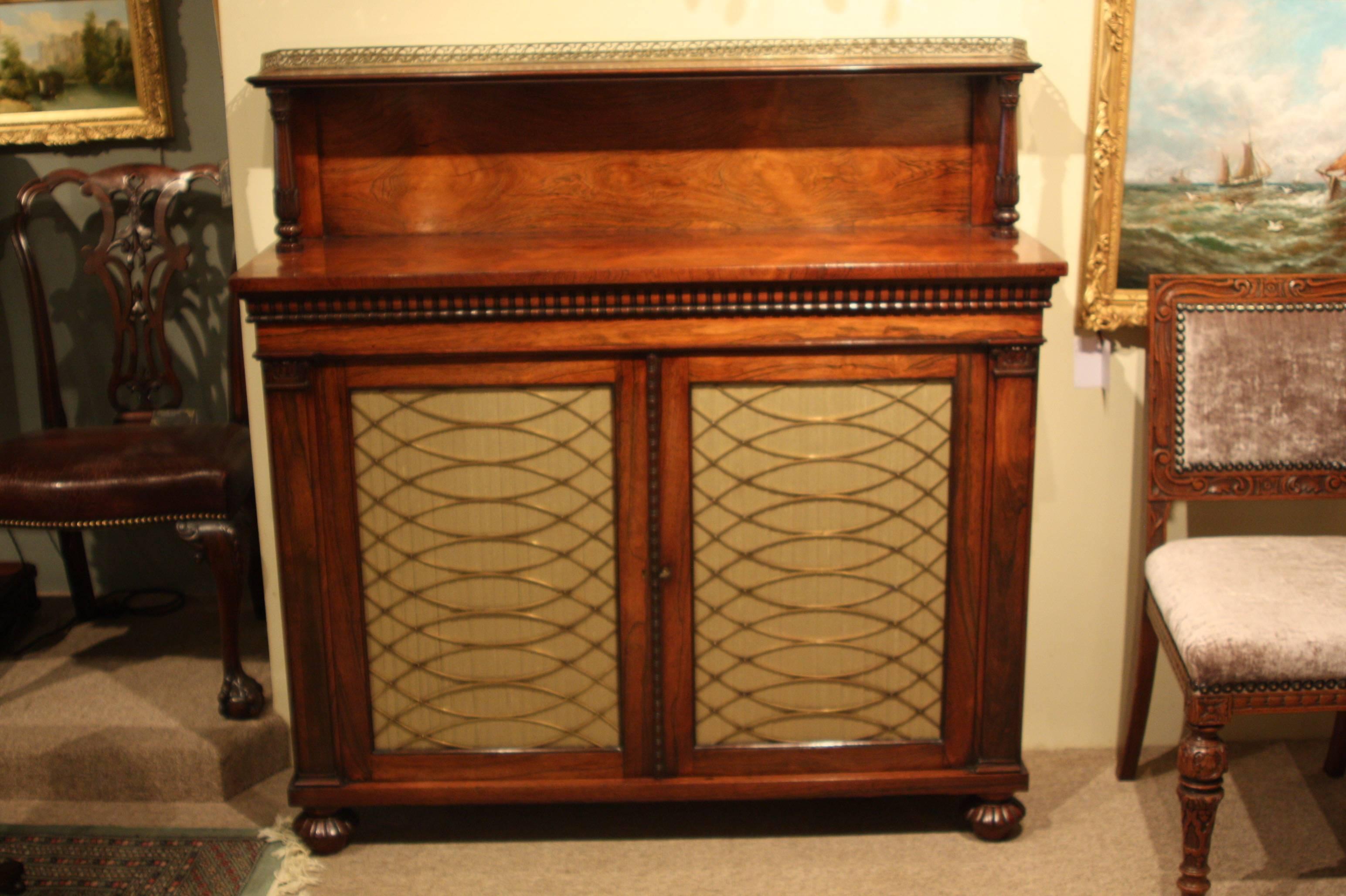 A fine Regency period rosewood chiffonier of exceptional quality, with a brass galleried ledge back over two brass grille doors, on melon carved feet. In the manner of Gillows.