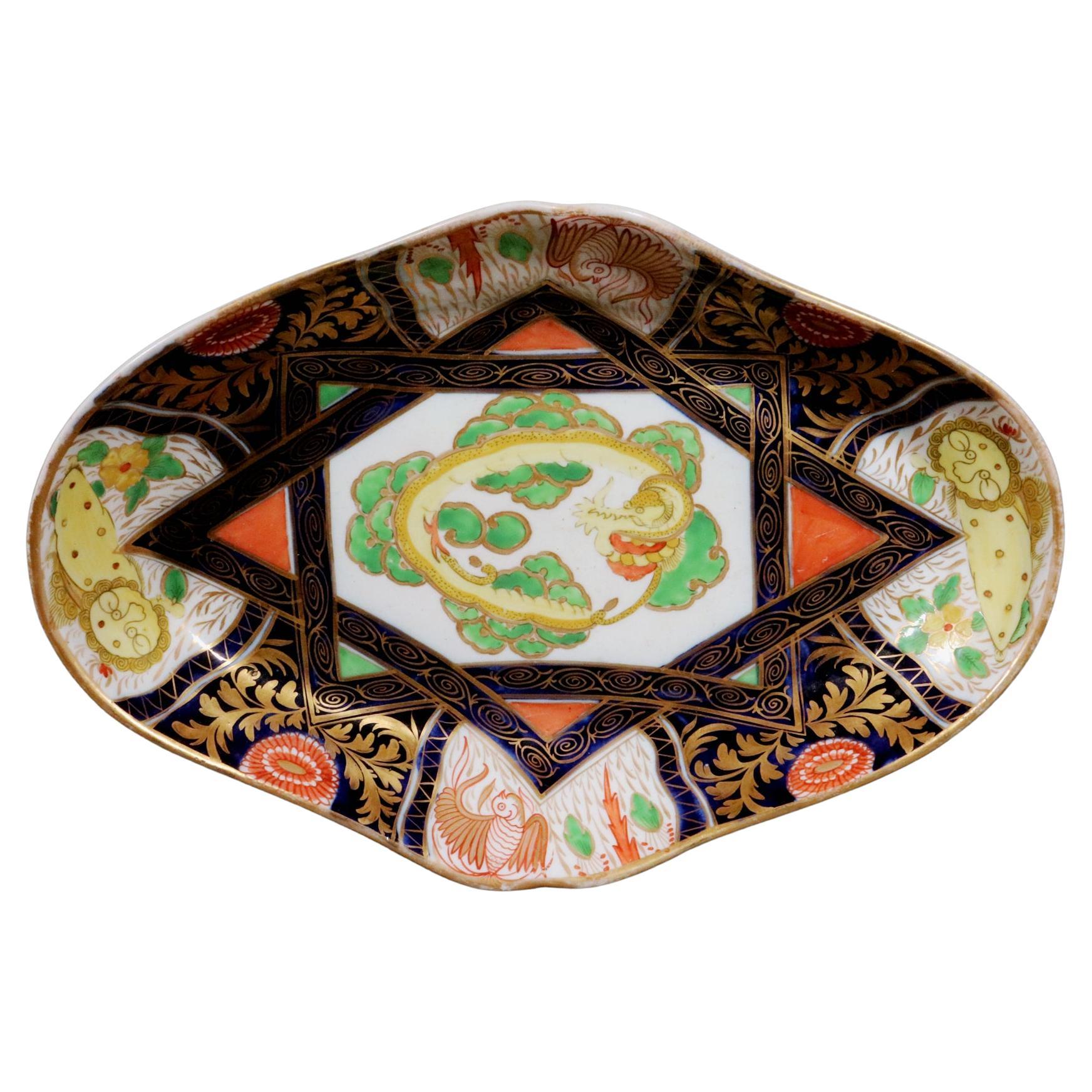 Coalport Porcelain Chinoiserie Dish with Yellow Dragon
Circa 1805-10

The Coalport porcelain shaped oval dish is painted in an Imari coloration with the center depicting a yellow dragon with green scales.  This has a double border of mazarine blue