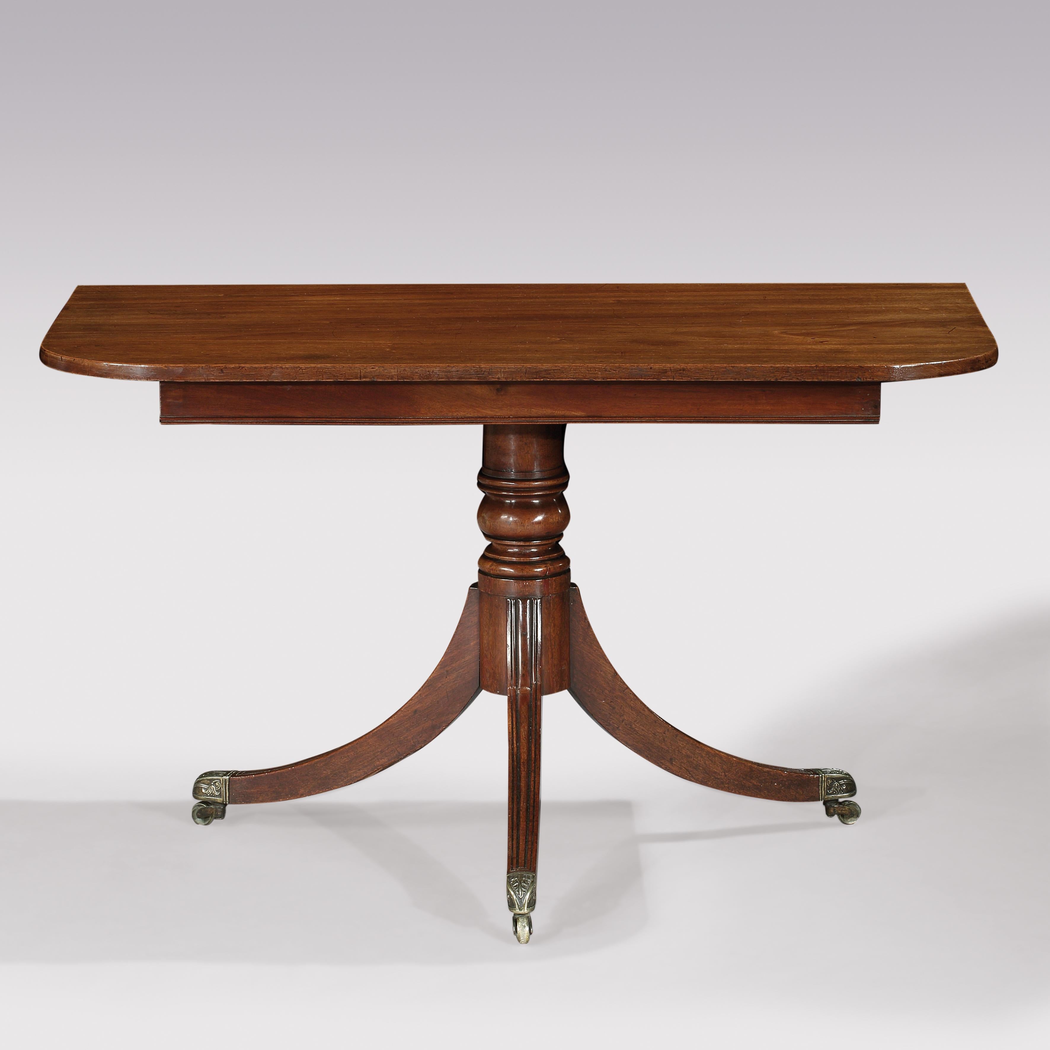 An early 19th century Regency Period well figured mahogany two pedestal dining table, having rectangular ends with rounded corners fitted with 1 original and 1 matching leaf, supported on ring turned baluster stems, ending on three splay moulded