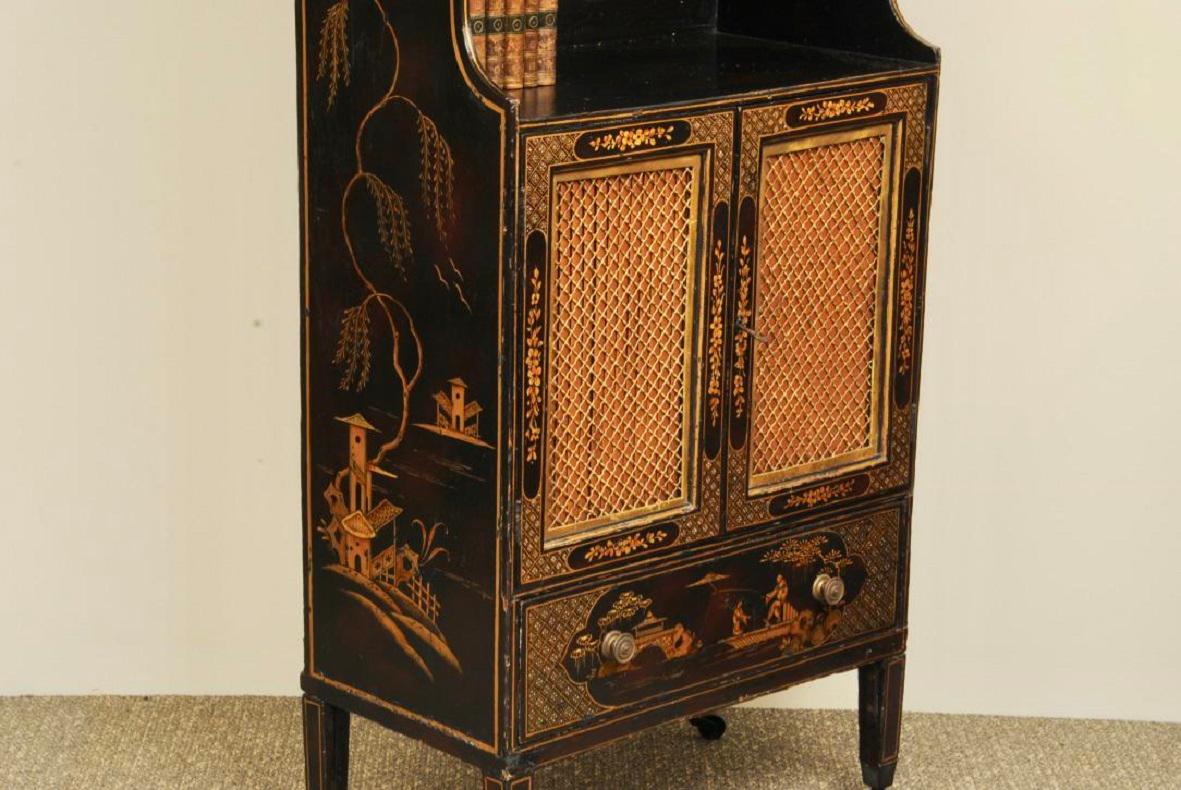Ein elegantes, schwarz und vergoldet lackiertes Bücherregal aus der Regency-Zeit, das auf quadratischen, spitz zulaufenden Beinen mit Originalrollen steht. Der gesamte Raum ist mit orientalischem Lack verziert. Lagerung der Originalgitter an den