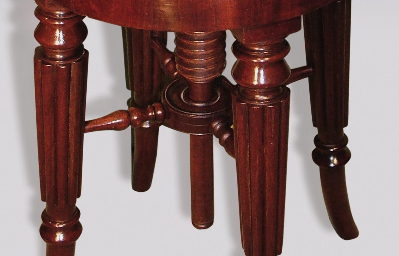 An early 19th century Regency period mahogany ‘Gillows’ music stool, having circular threaded revolving seat, supported on turned reeded legs with outswept feet.
