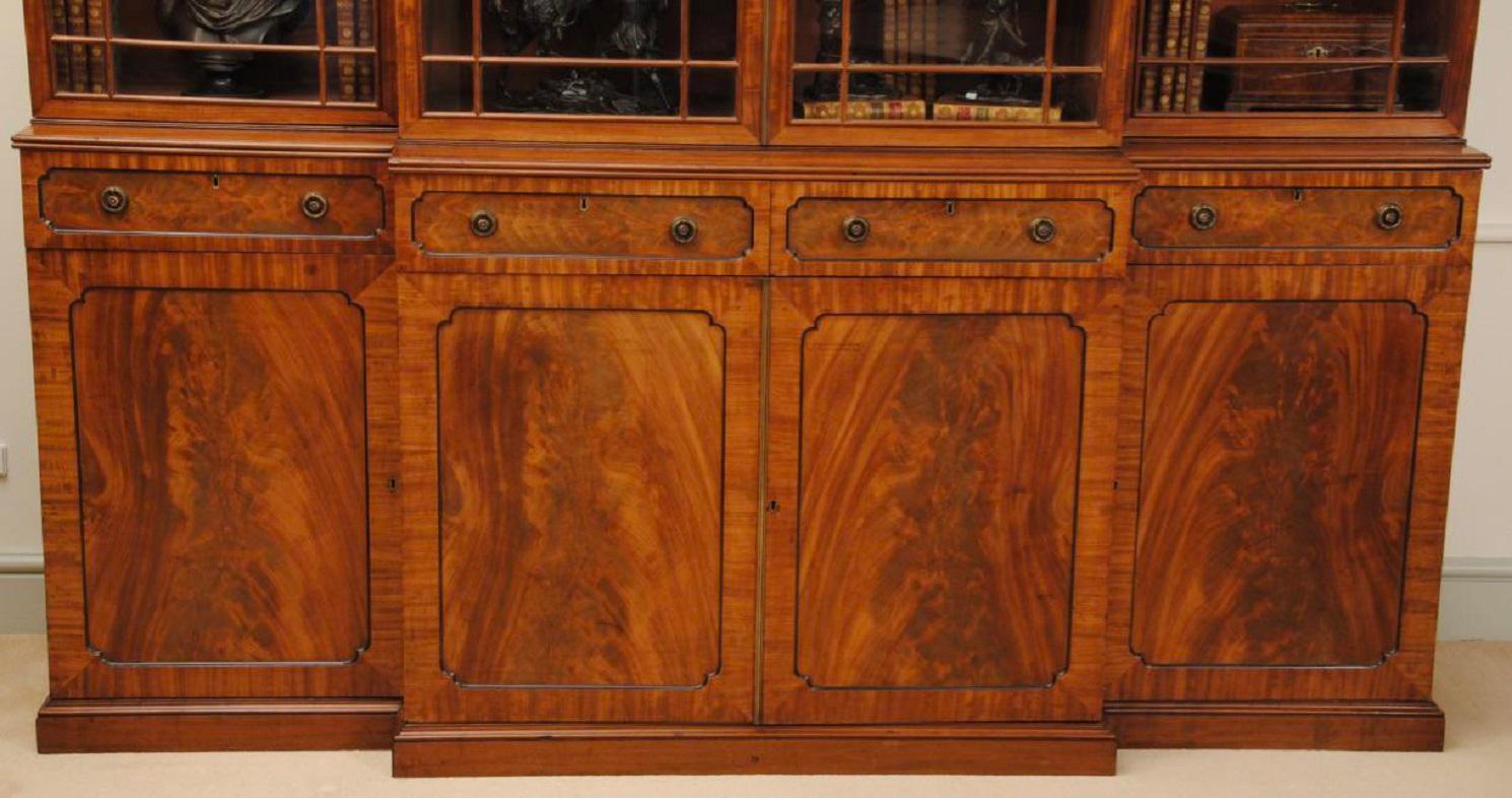 A small elegant regency mahogany breakfront bookcase with ebony details and flame veneers to the door fronts, superb mellow colour and good patination. The lovely bookcase is in the manner of Gillows of Lancaster. A fantastic piece.