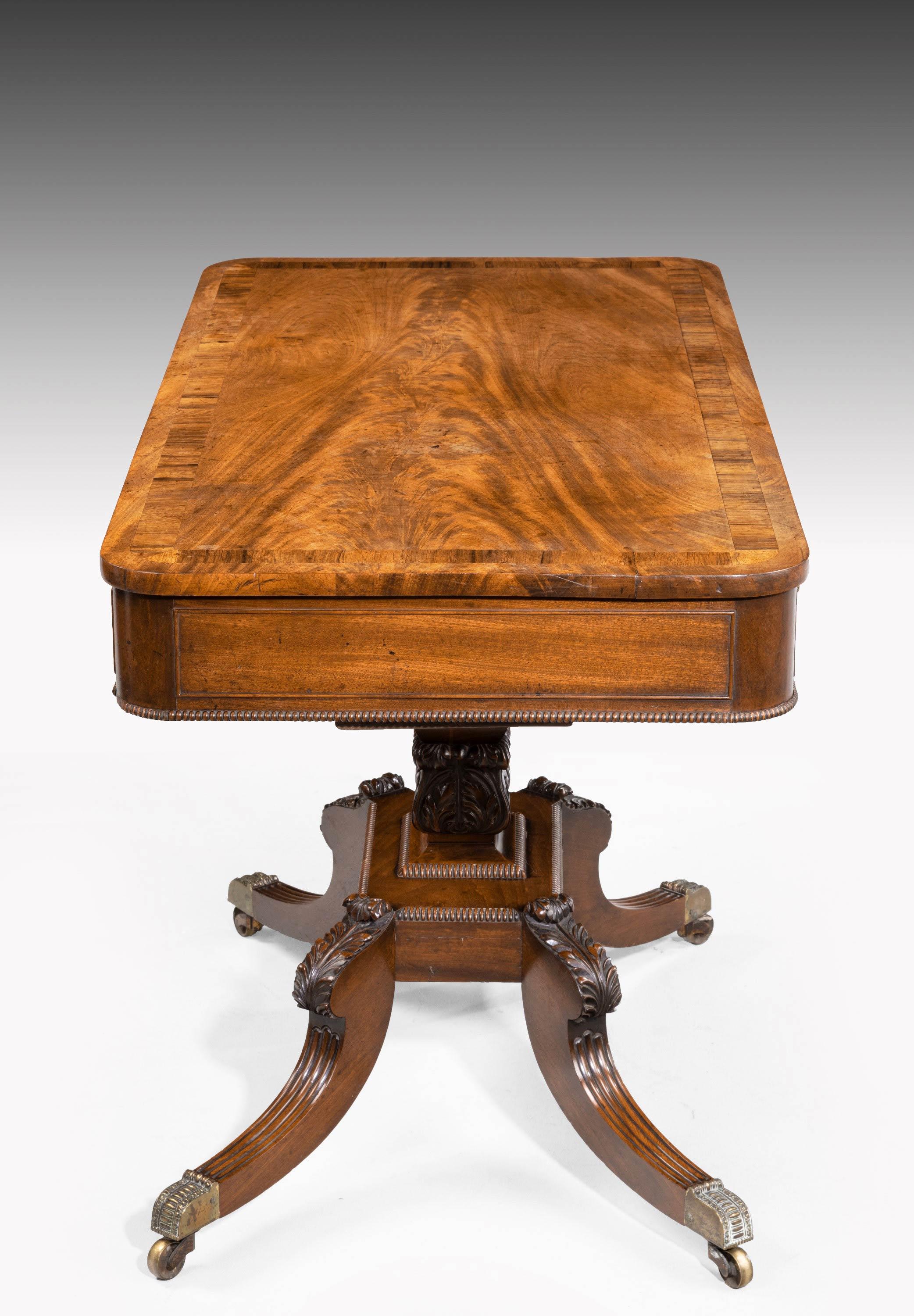 A very fine quality centre standing Regency period mahogany table. With a very finely figured top and rosewood crossbanding. Carved rectangular pod with beautifully carved acanthus leaves to the top of the termini. Original shoes, castors and gilt