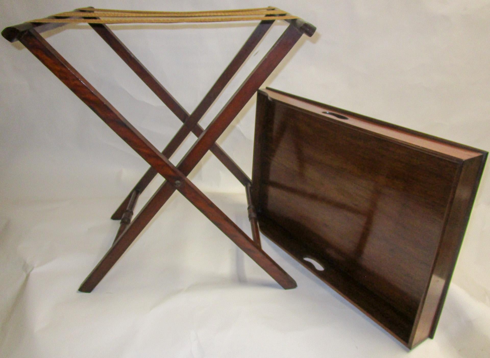 Regency period mahogany butlers tray on stand featuring a rectangular shaped tray with surround gallery. A slight slope terminates to one side with handles on either side. On folding X-frame stand with heavy woven straps to accommodate the tray.