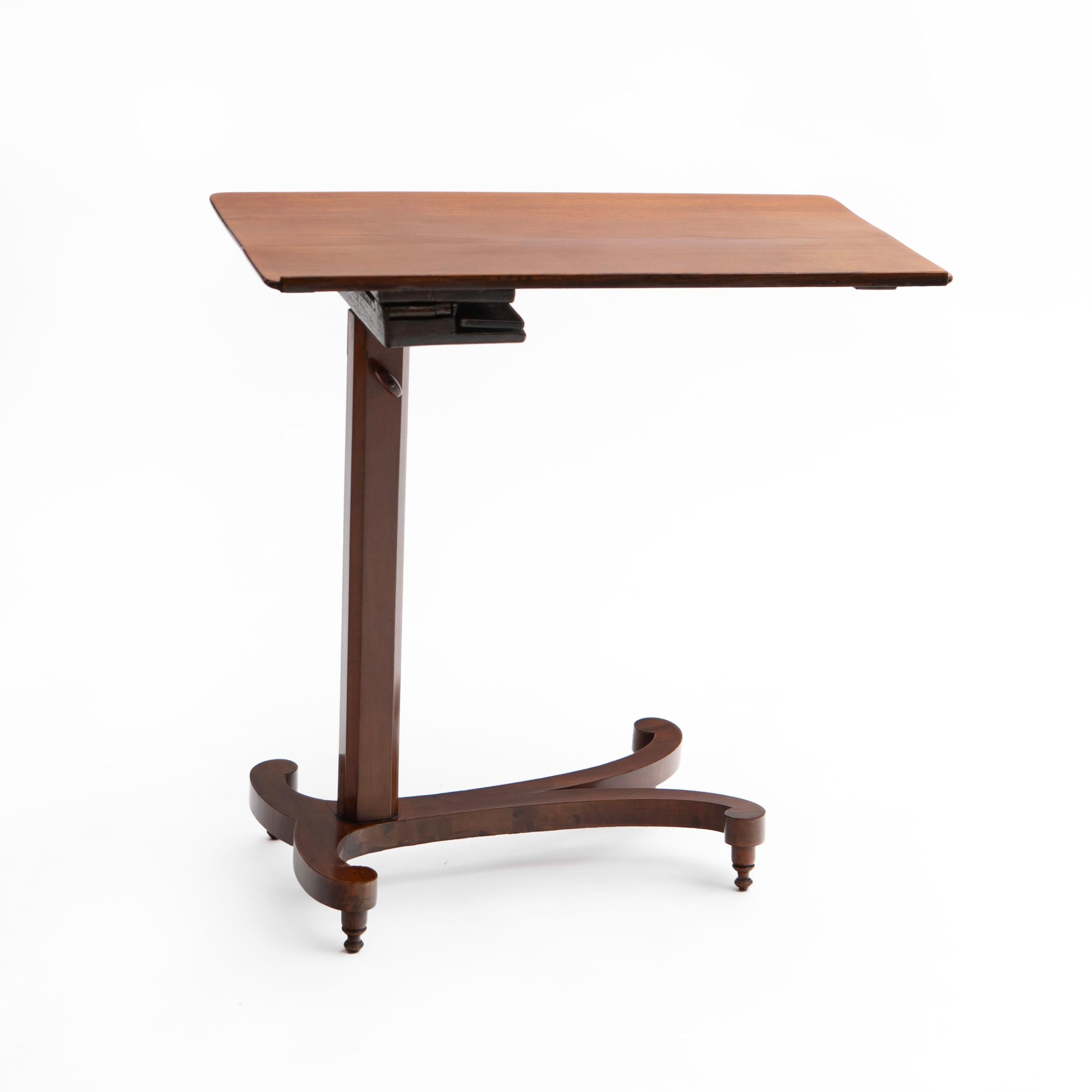 An elegant Regency period mahogany lectern or reading bedside table.
The table is featuring a tabletop may be tilted flat or angled and has a small latched ledge to hold a book. It also has a base that expands to change the height, adjustable from: