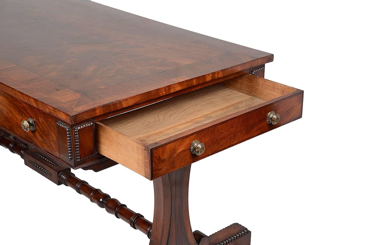 A good quality Regency period mahogany end support library table, having a crossbanded top, drawers and dummy drawers to the frieze. Raised on out swept carved end supports, with a stretcher between, terminating in block and turned feet.