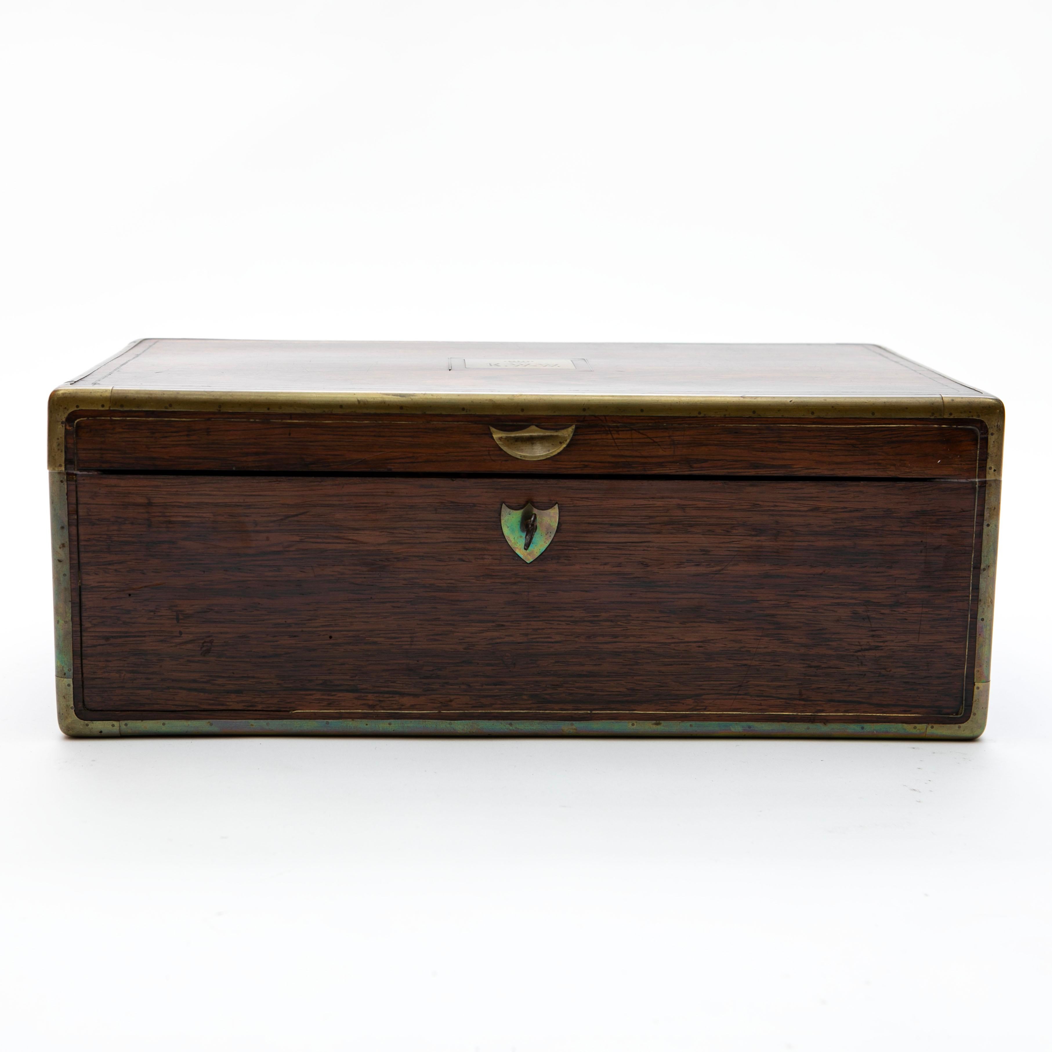 Caja de escritura de viaje de campaña de la época de la Regencia, Inglaterra, hacia 1820.
Hecho para un militar.
Fabricada con madera de palisandro de alta calidad, la caja tiene cantos protectores de latón en todas las esquinas. La tapa está