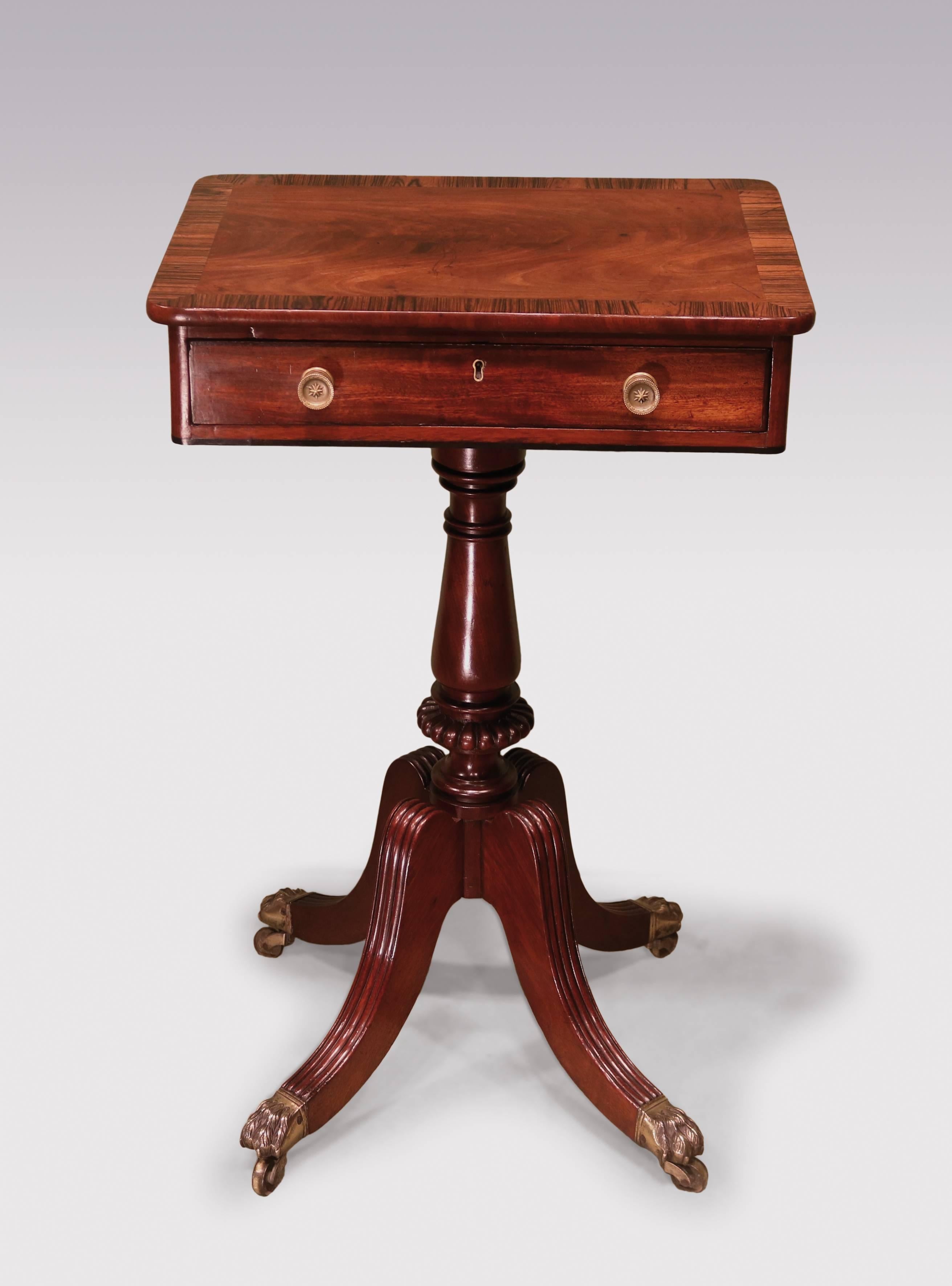 An early 19th century Regency period mahogany occasional table, having flame figured top with rosewood crossbanding, above frieze drawer, supported on ring-turned column, ending on four-splay reeded legs retaining original lion's paw castors.