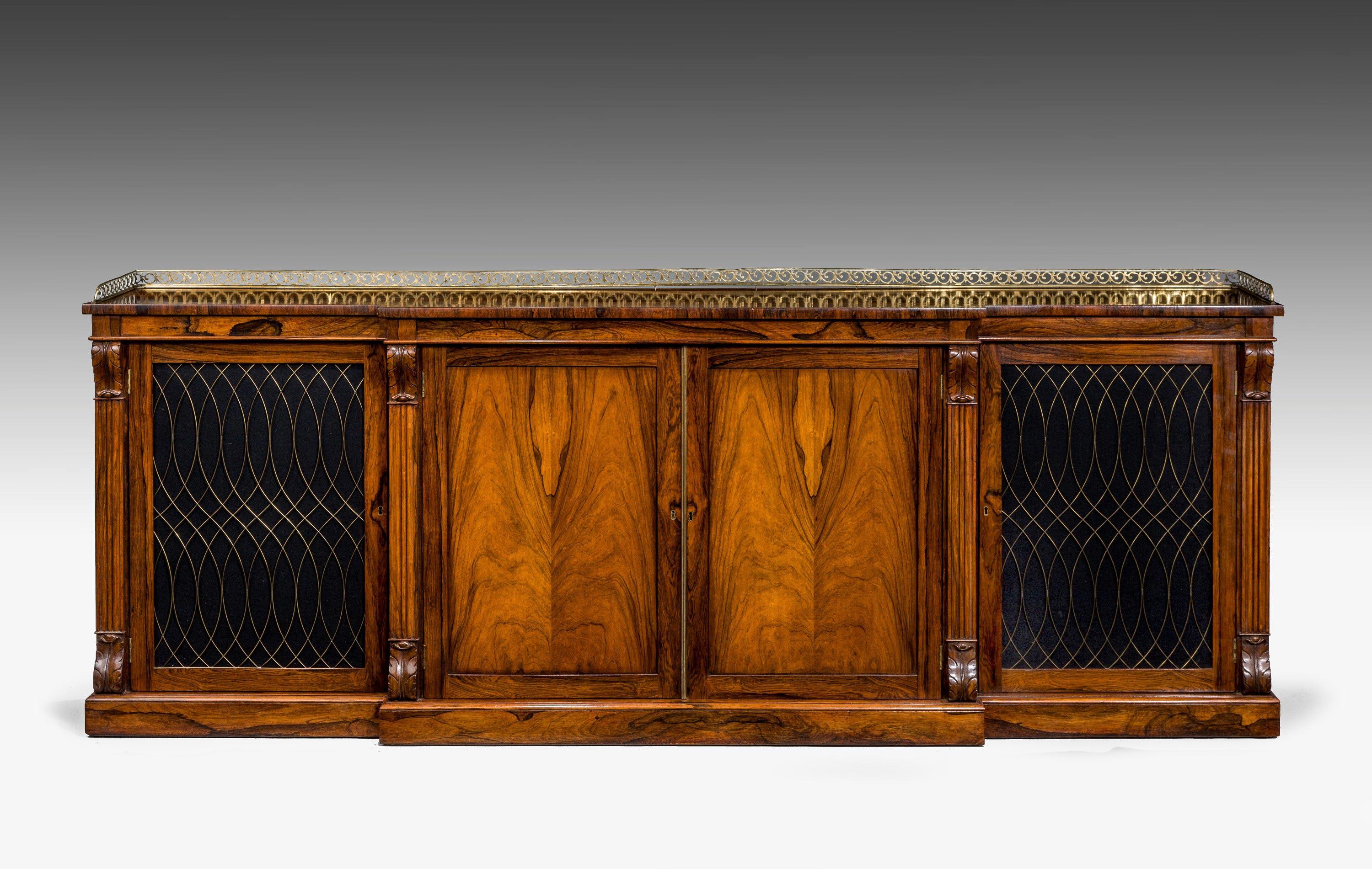 A very well figured Regency period breakfront side cabinet surmounted with a good pierced gallery and fine brass grills to the end panels with anthemion leafs to the top and bottom capitals.