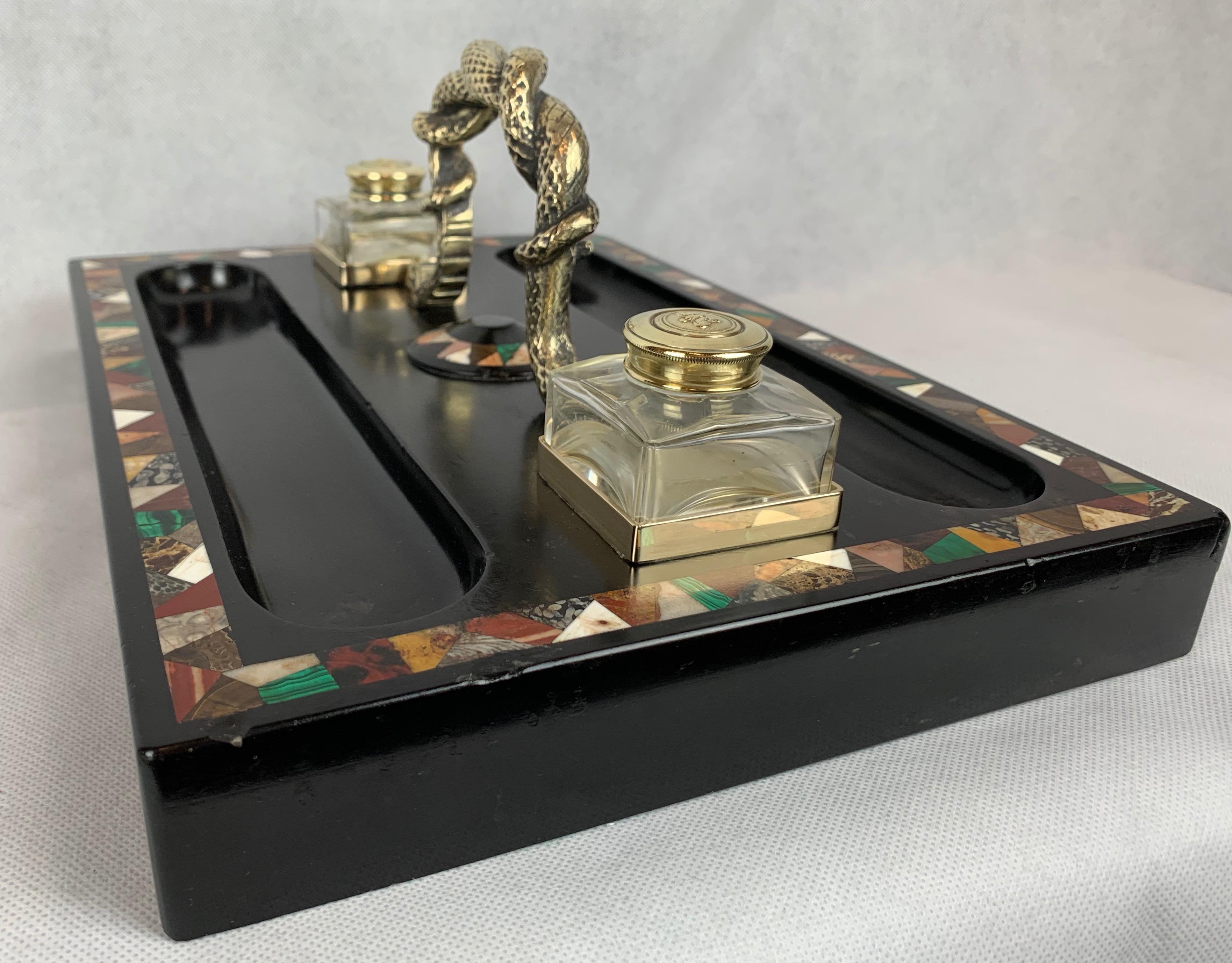 Large English Regency inkstand originally created for a partner's desk with a bronze handle of entwined serpents. The matching blown crystal inkpots have lids with embossed crowns. The Pietra Dura band on the base is set into Belgian black marble.