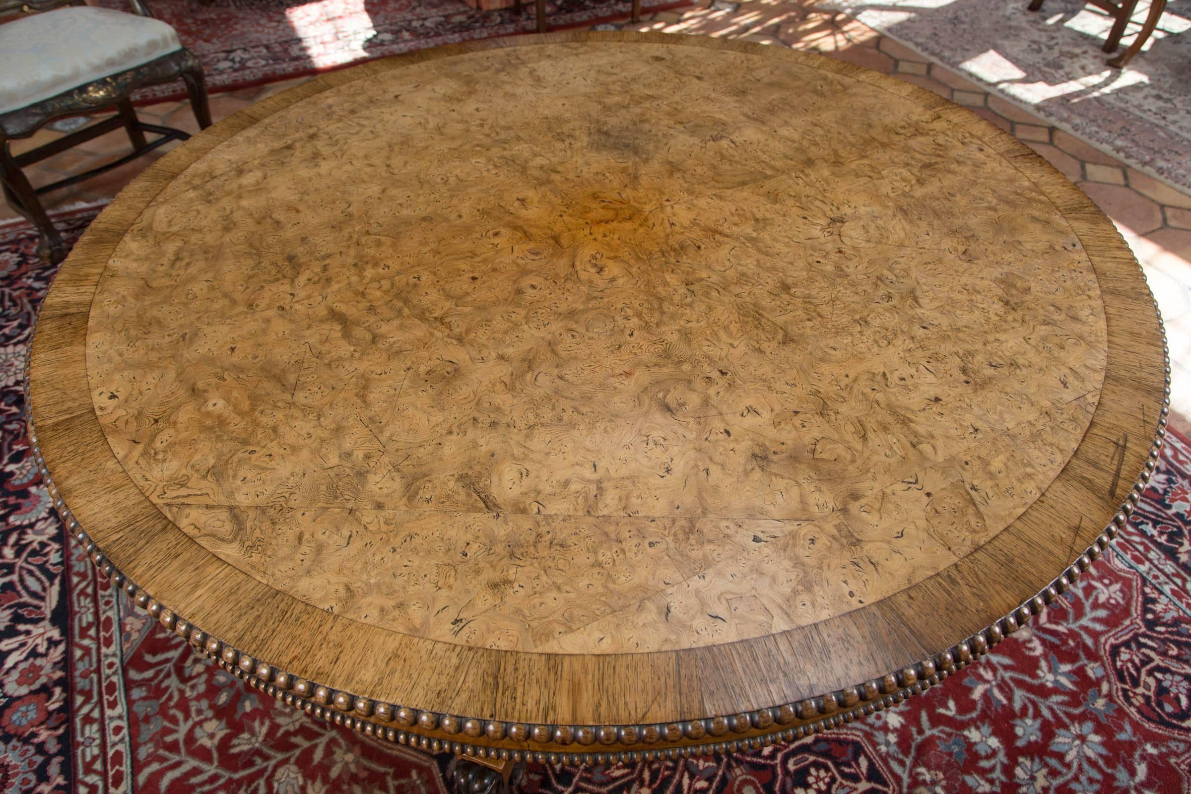 English Regency pollard oak centre table with oak crossbanding. Table features large beaded edge over apron with smaller beaded edge. Concave, four-sided column resting upon concave, four-legged platform base, ending with ebonized carved claw feet