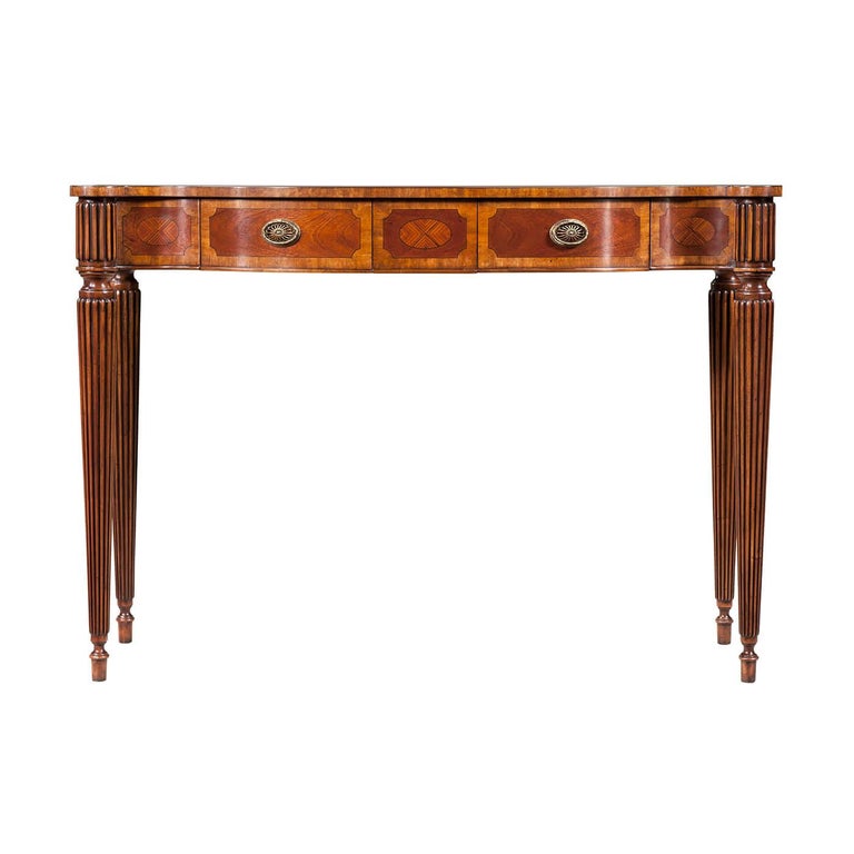 A Regency style bowfront console with figured mahogany, eucalyptus, and rosewood crossbanding, the serpentine top with a bowed front and sides centered by a rosewood oval inlay, the banded frieze with two frieze drawers with natural brass handle, on