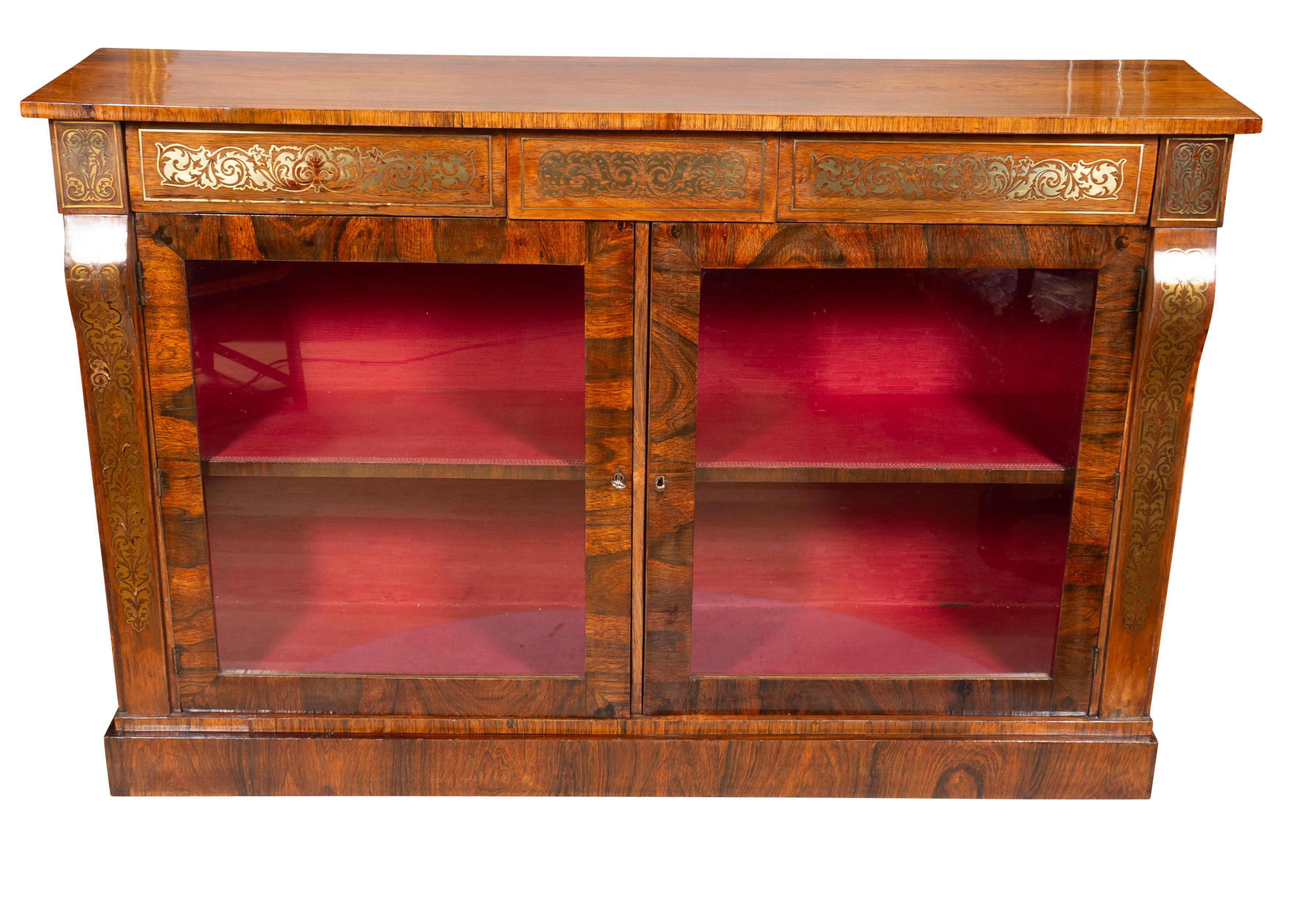With a rectangular top over a brass inlaid frieze with two drawers over a pair of cabinet doors with key. Plinth base. One shelf.
