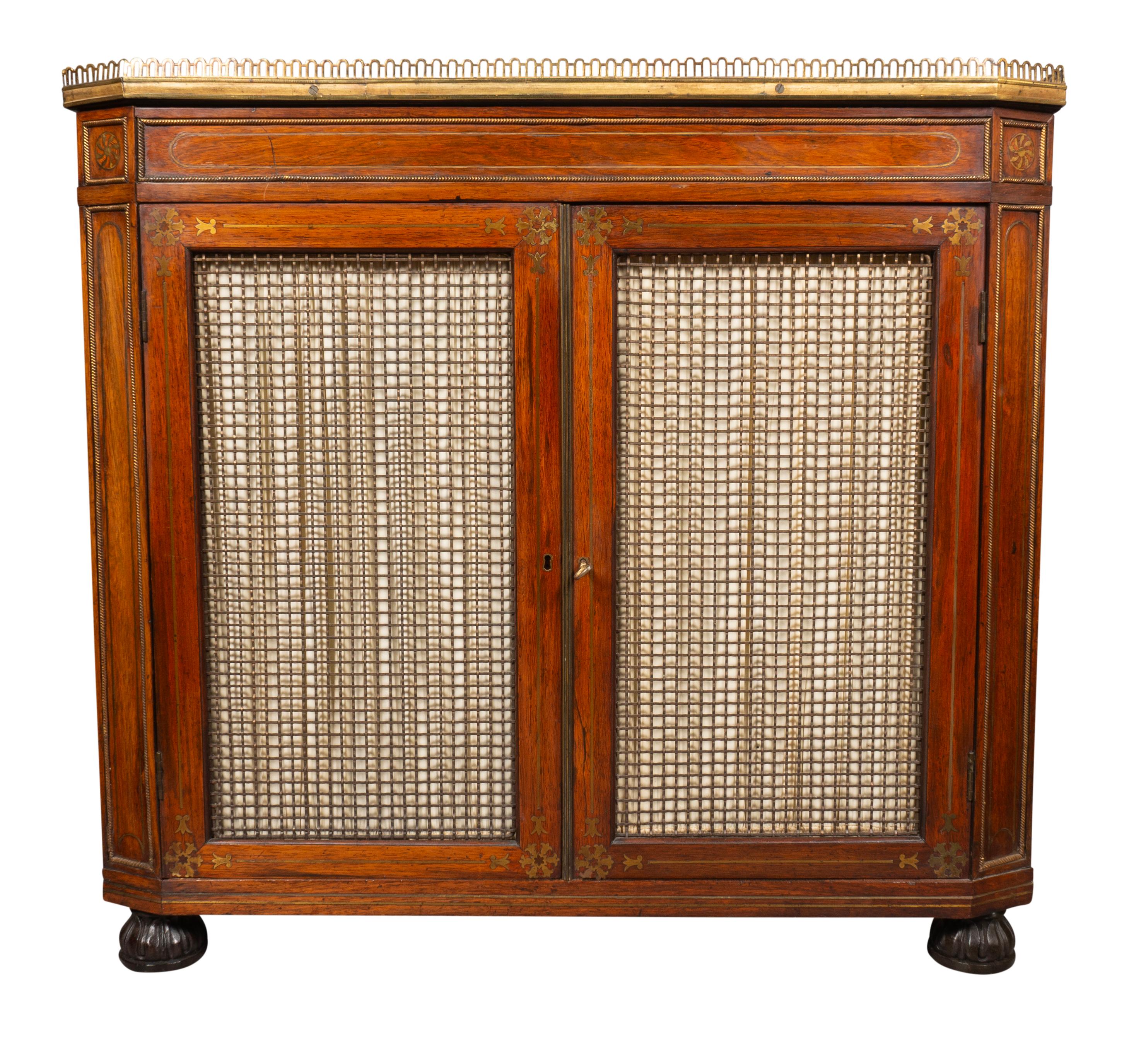 Rectangular top with brass gallery over a pair of grill doors with brass inlay in the manner of John McLean.
Chamfered ends with brass wheel inlay.. Carved bun feet.