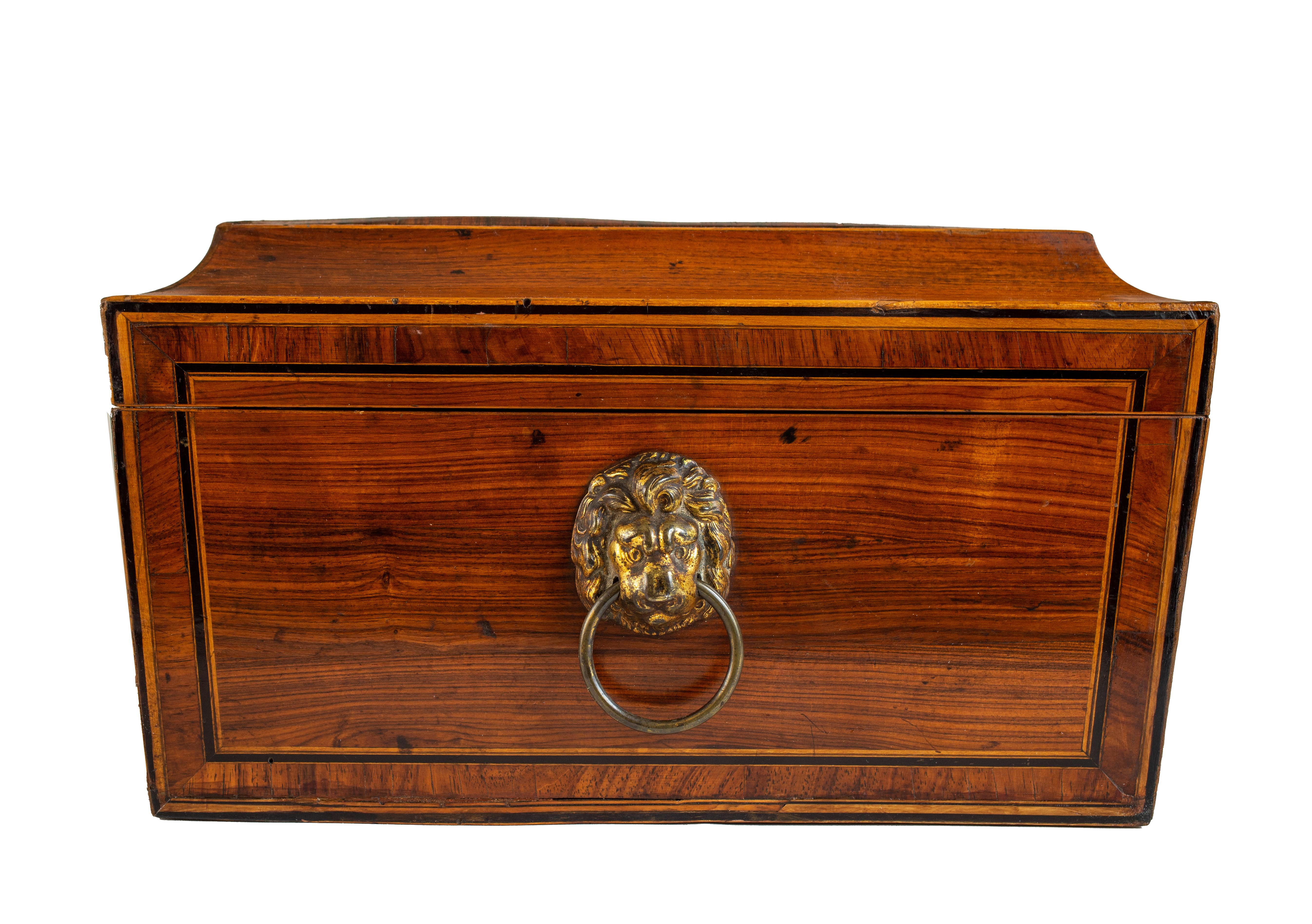 Of rectangular shape, inlaid with boxwood and ebony, with brass lion head handles on each side and a vintage satin-lined interior. With a key.