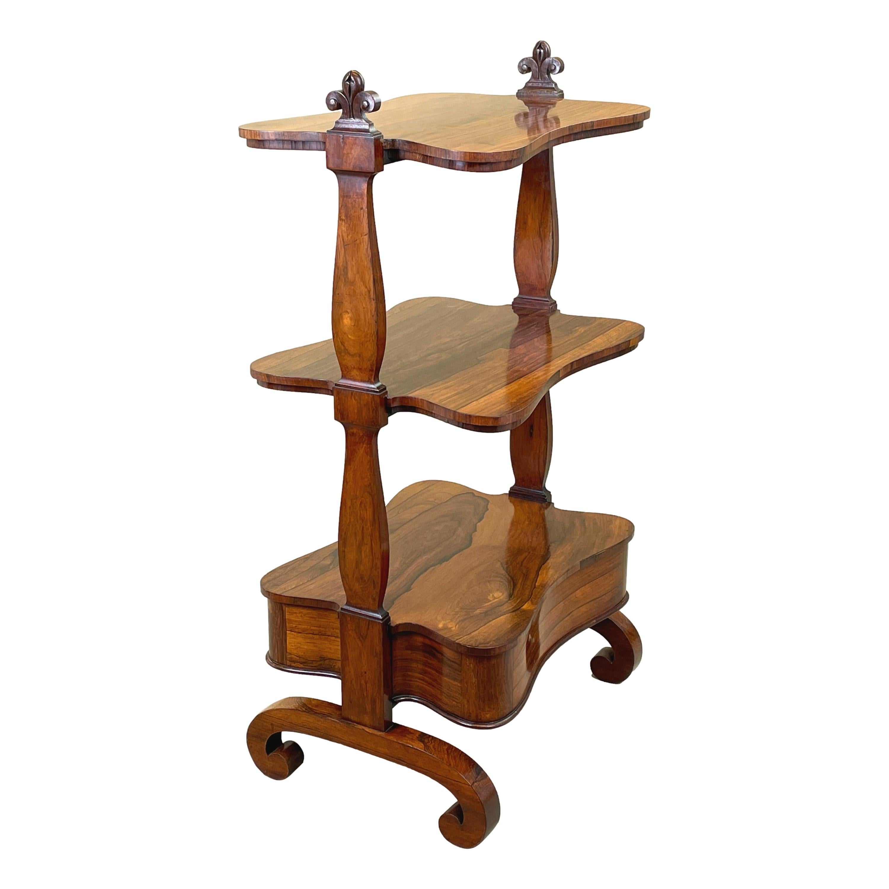 A very good quality English regency period 19th
century rosewood whatnot of unusual shape having
three well figured tiers united by elegant silhouette
end supports over one mahogany lined drawer
retaining original turned wooden knobs

(This